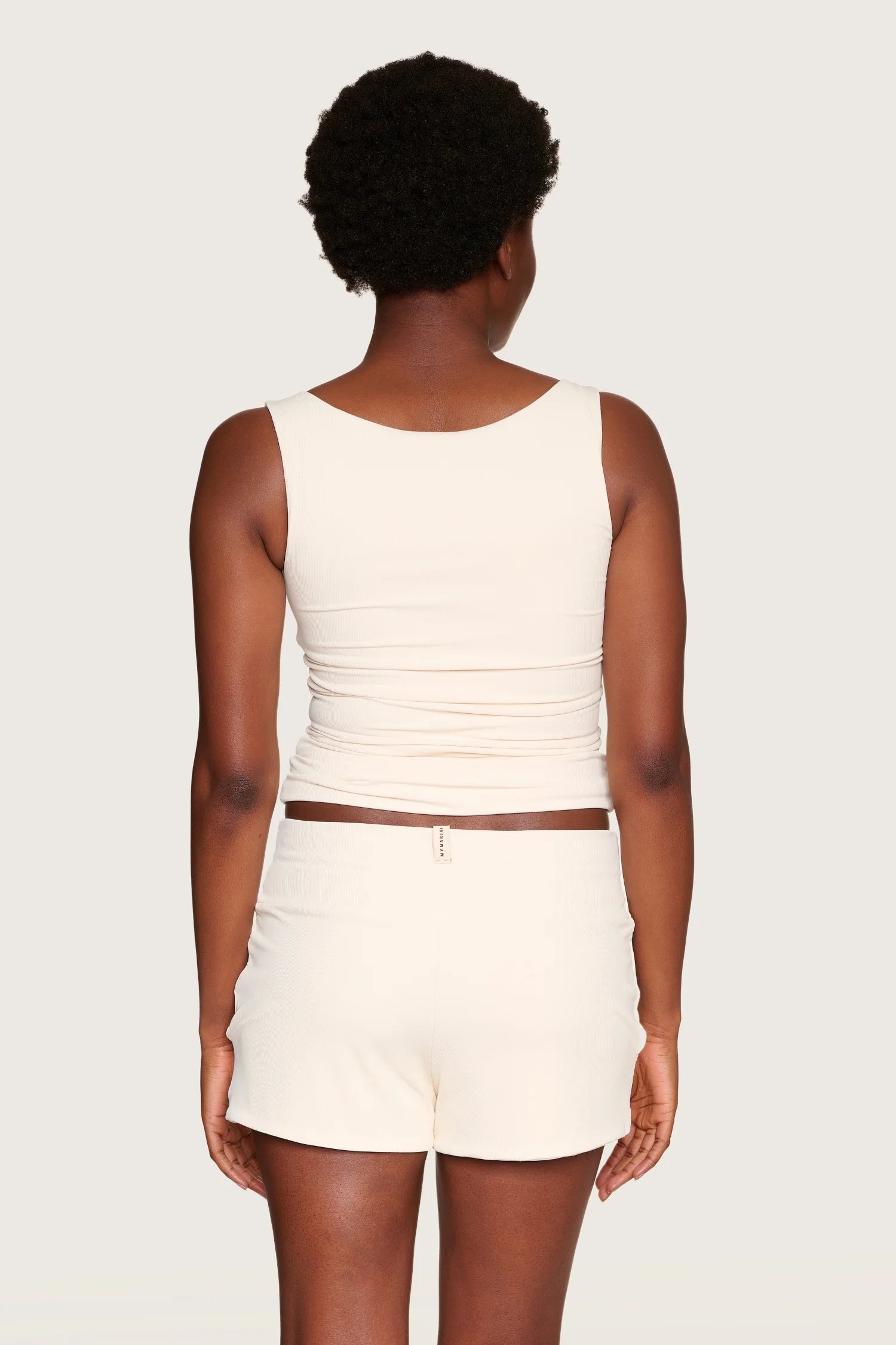 Person von hinten in cremefarbenem MYMARINI-Top mit breiten Trägern und passender Hose.#color_off-white