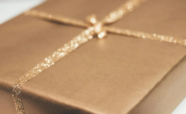 Nahaufnahme eines goldfarben verpackten Geschenks mit glitzernder Schleife.