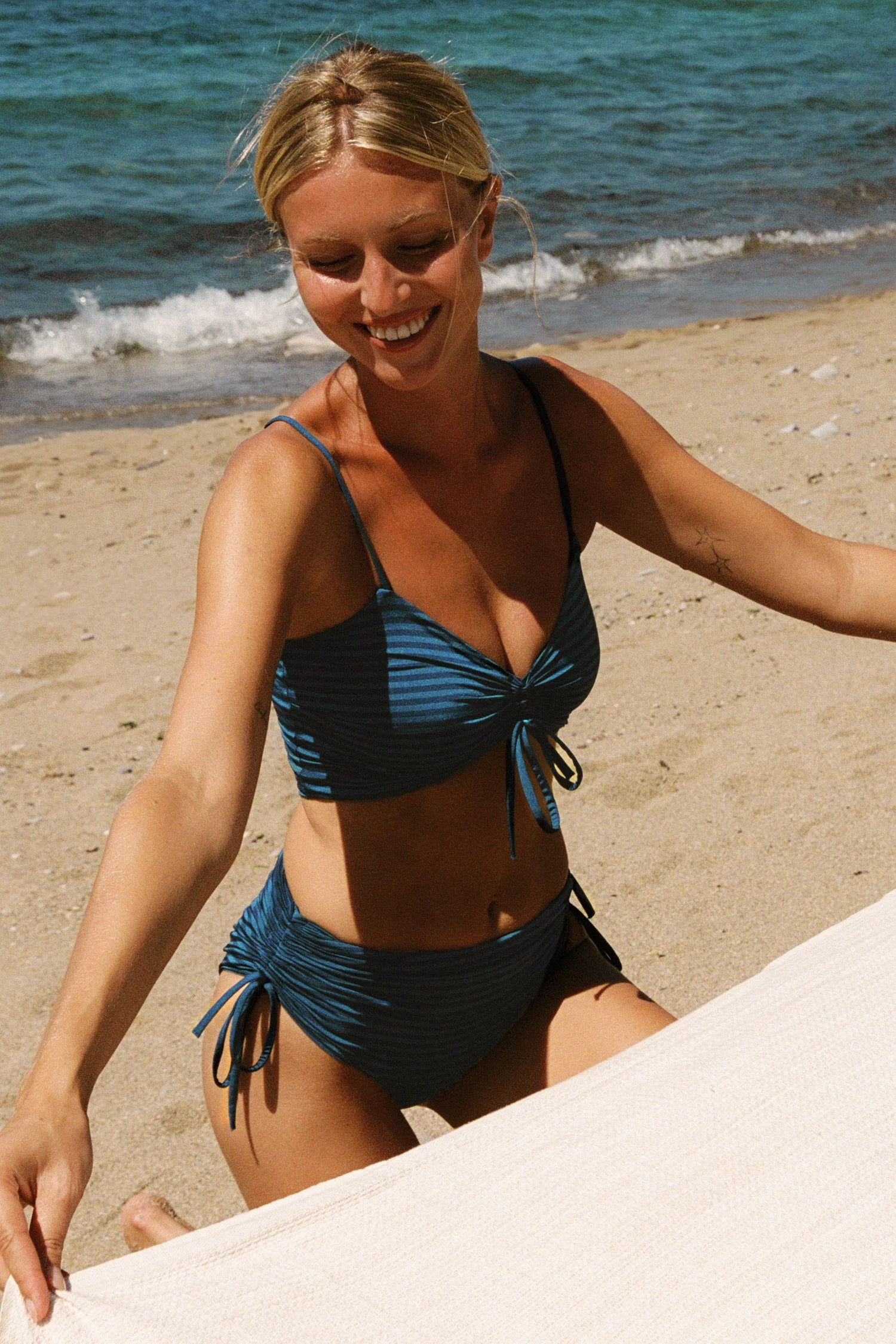 MYMARINI Bikinitop mit Spaghettiträgern und V-Ausschnitt sowie Bikinihose mit Kordelzug, am Strand.#color_cave-striped
