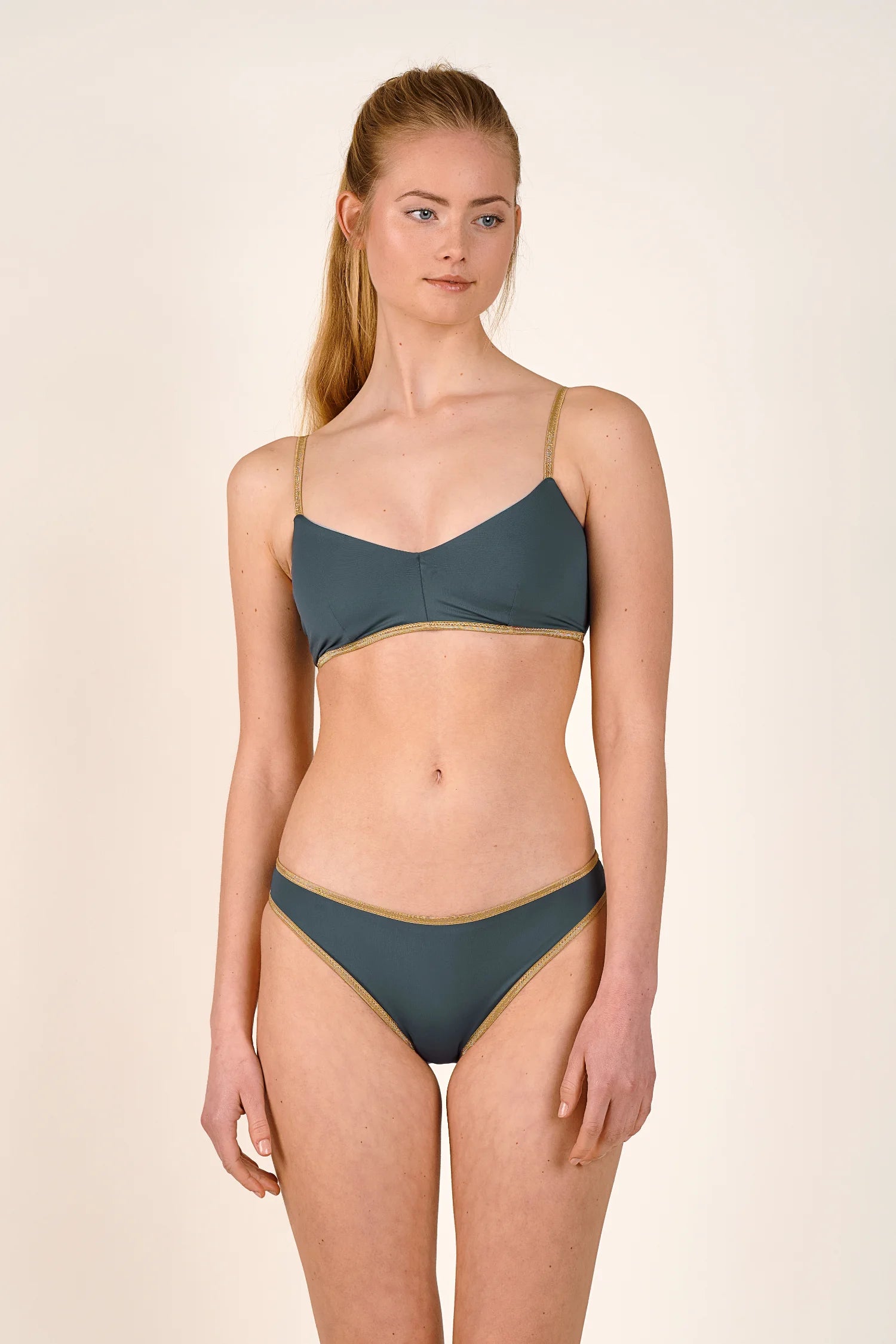 Frau trägt MYMARINI Bikini mit Spaghettiträgern und hohem Beinausschnitt in Dunkelgrün.#color_crystal-grey