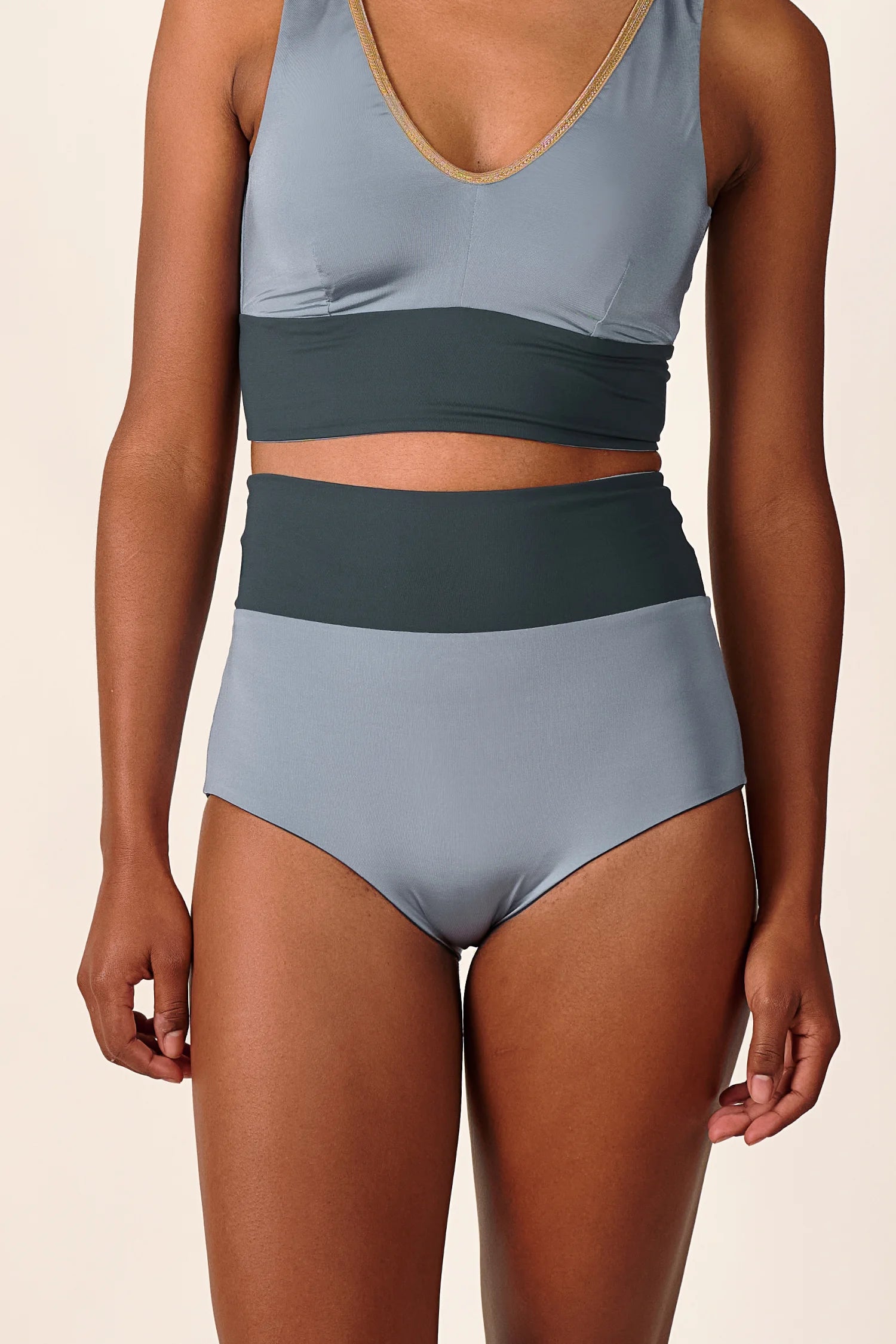 Person trägt MYMARINI Bikinitop mit V-Ausschnitt und Bikinihose mit hohem Bund in Grau und Dunkelgrün.#color_crystal-grey
