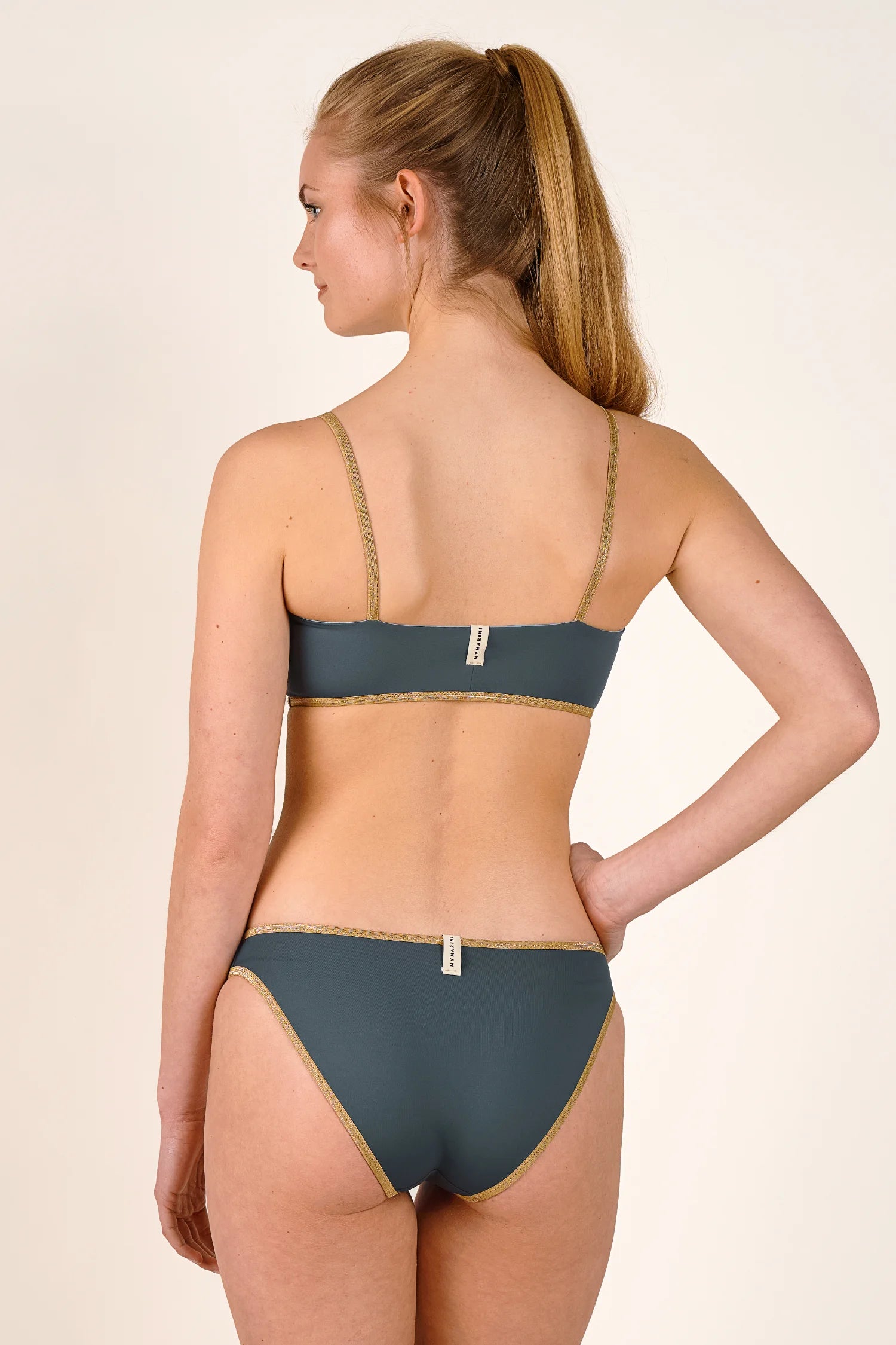 Frau in MYMARINI Bikini mit Spaghettiträgern und hohem Beinausschnitt, Rückansicht.#color_crystal-grey