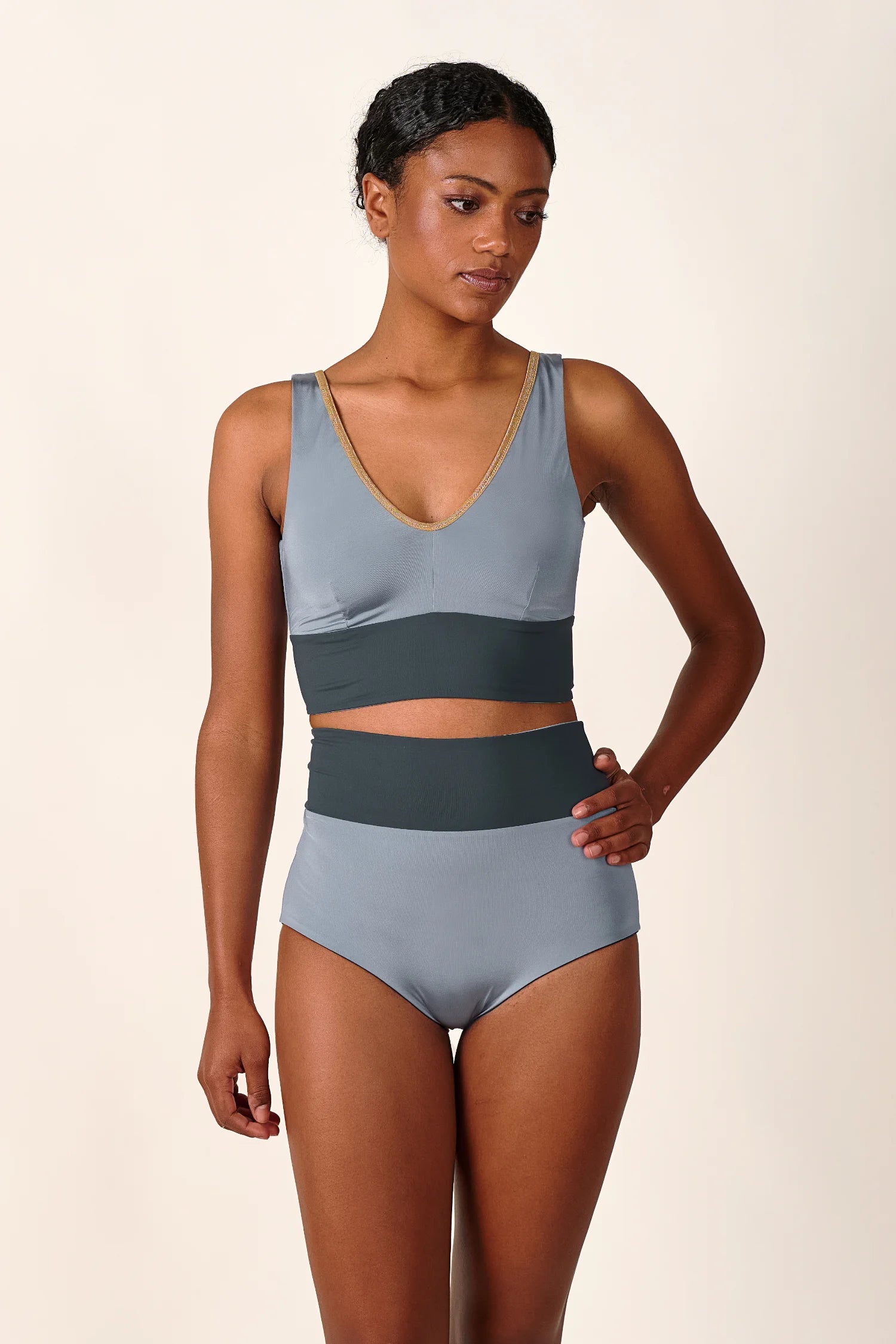 Frau trägt MYMARINI Bikini mit V-Ausschnitt und High Waist Schnitt in Grau.#color_crystal-grey