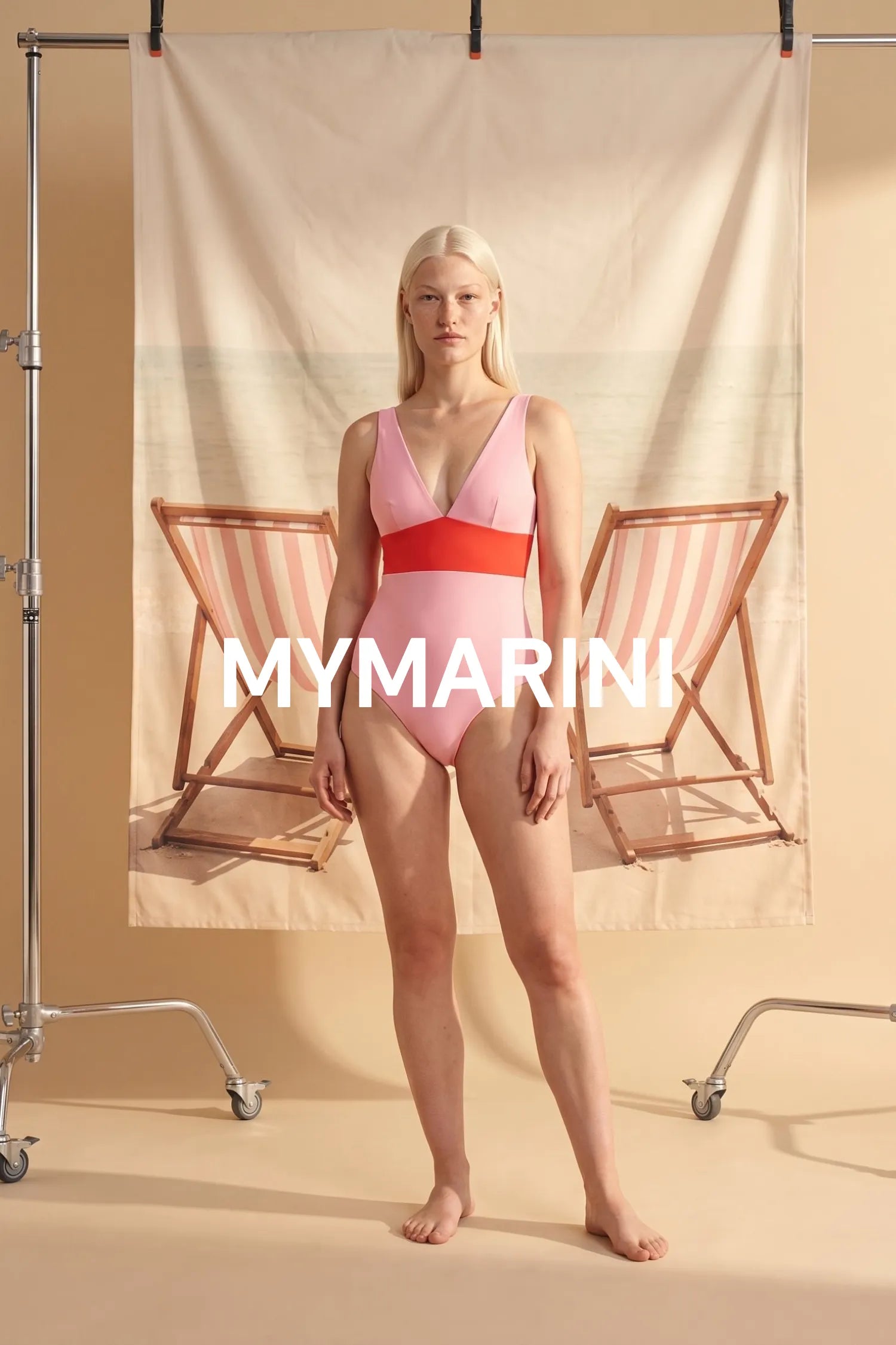 AI-generated, Model wearing the MYMARINI swimsuit with a V-neckline in poppy-macaron by beach chairs