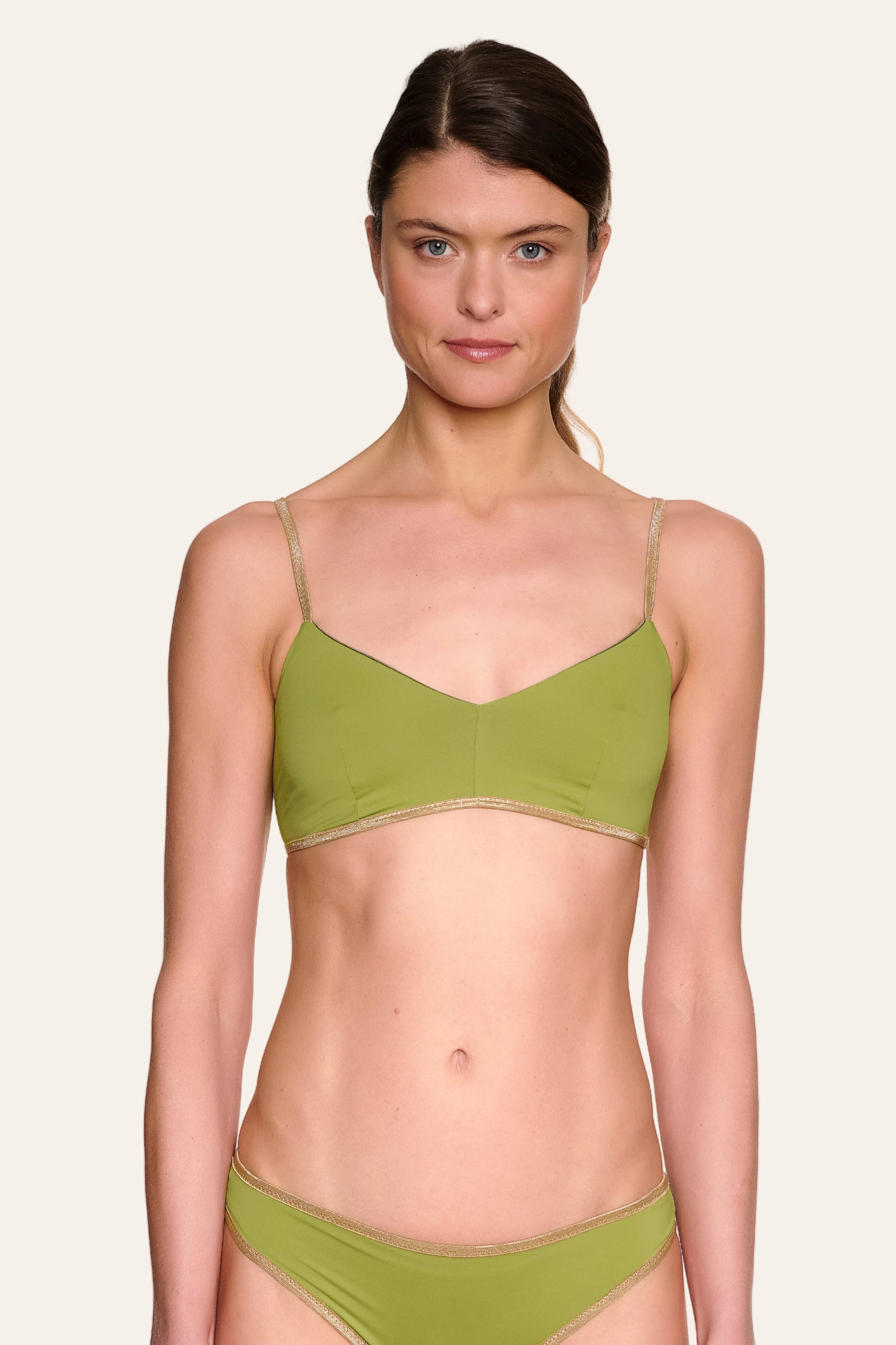 Frau trägt MYMARINI Bikinitop mit Spaghettiträgern und Bikinihose in Olivgrün vor neutralem Hintergrund.#color_apple-leaves
