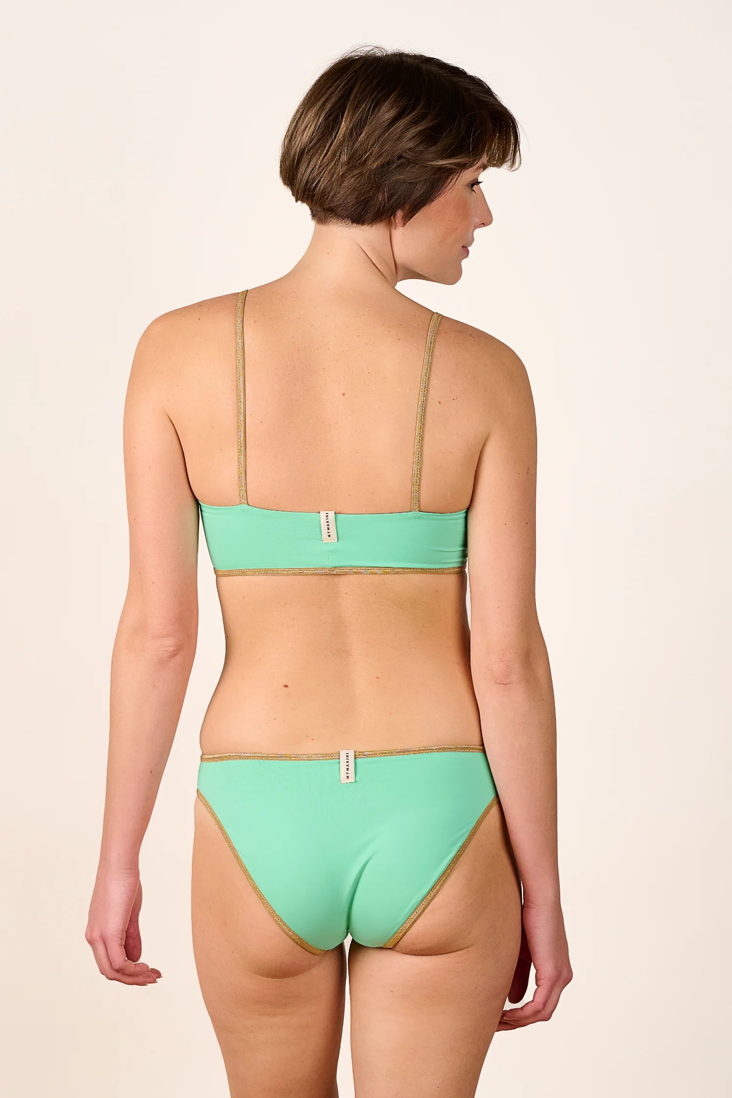 Frau trägt MYMARINI Bikini mit Spaghettiträgern und hohem Beinausschnitt in Mintgrün, Rückansicht.#color_lagoon-teal
