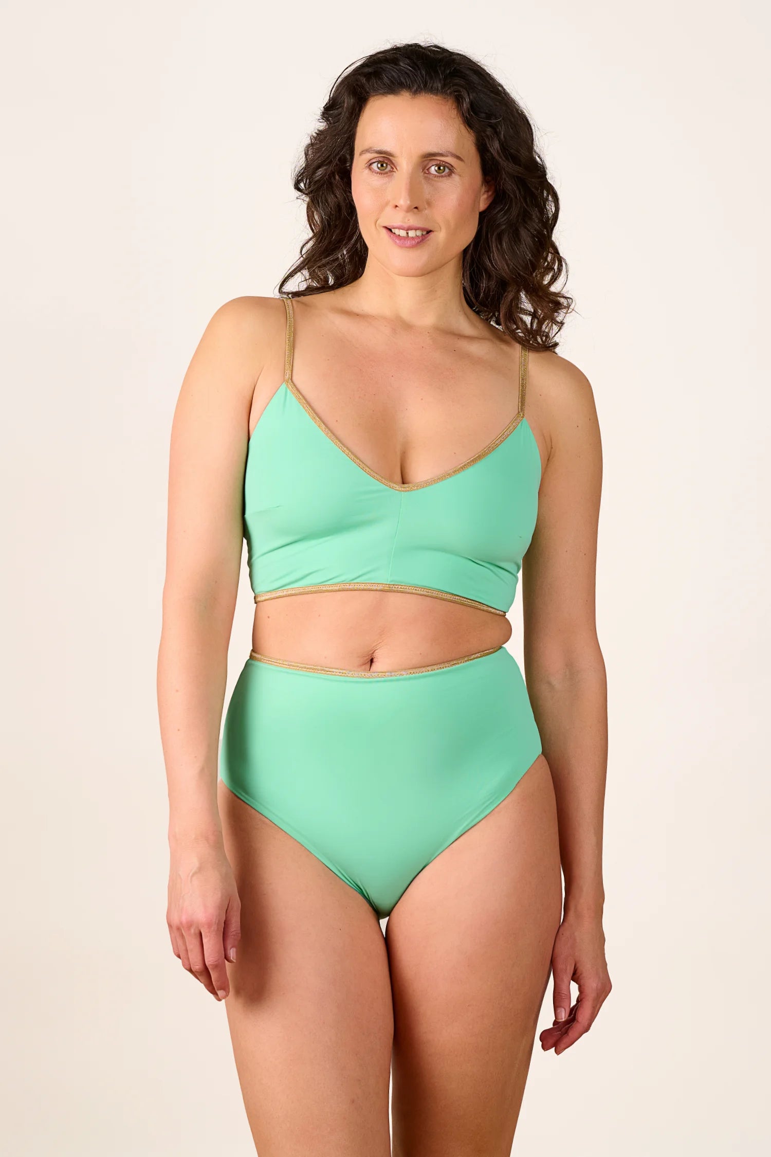 Frau trägt MYMARINI Bikinitop mit V-Ausschnitt und Spaghettiträgern sowie High-Waist-Bikinihose in Mintgrün.#color_lagoon-teal