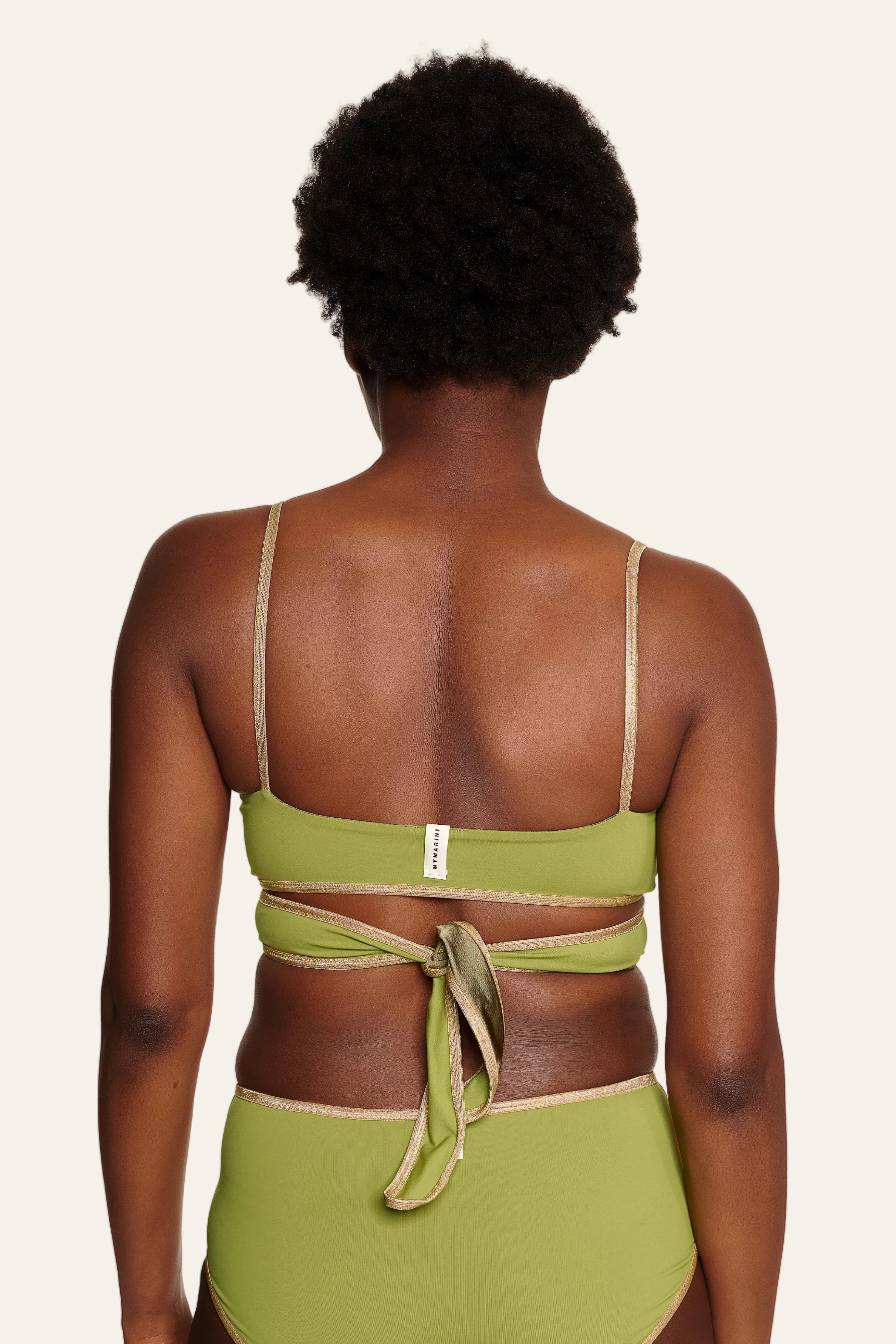 Person von hinten in grünem MYMARINI-Bikini mit Spaghettiträgern und hohem Beinausschnitt.#color_apple-leaves
