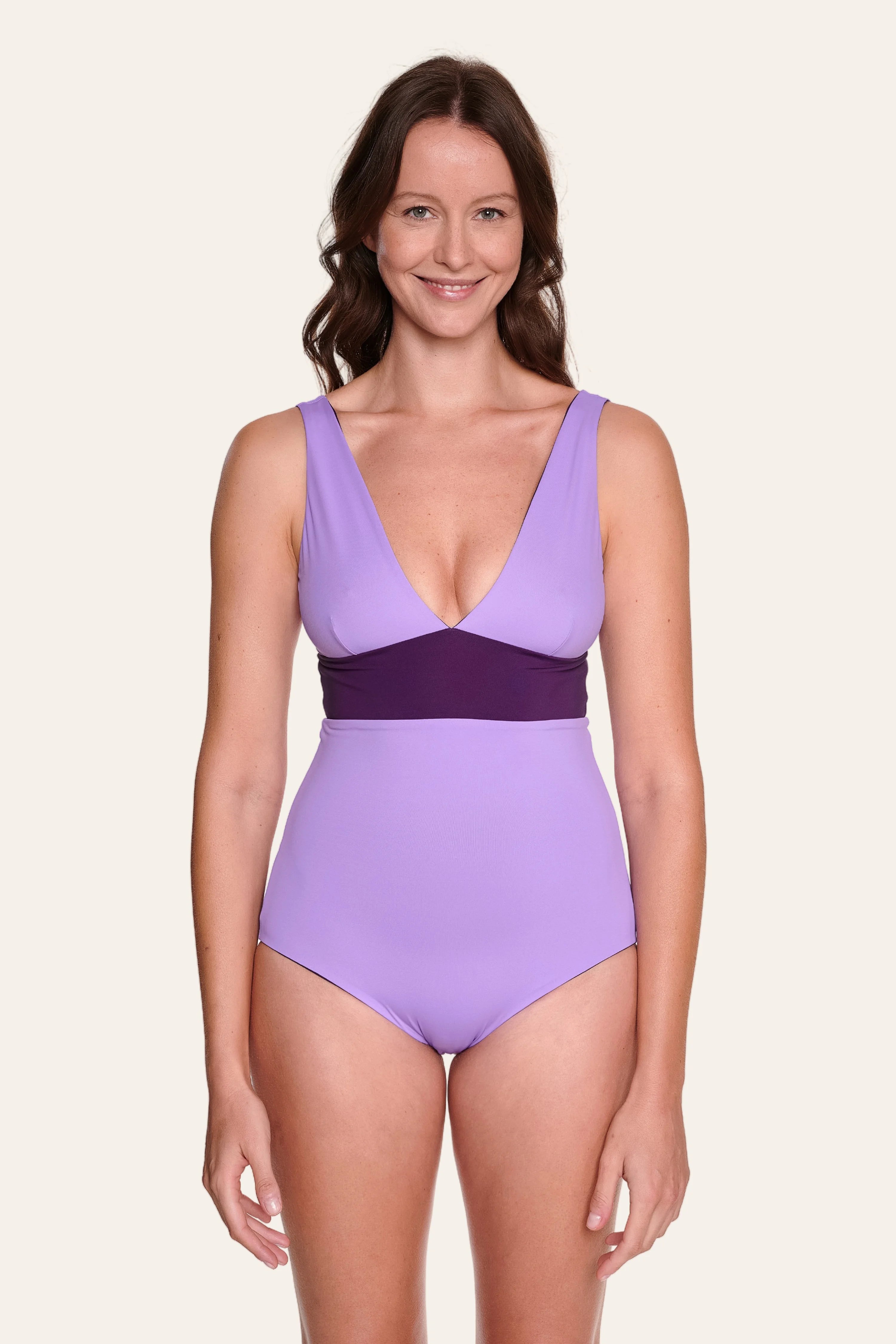 Frau trägt MYMARINI Badeanzug mit V-Ausschnitt und breiten Trägern in Lila.#color_lavender-plum