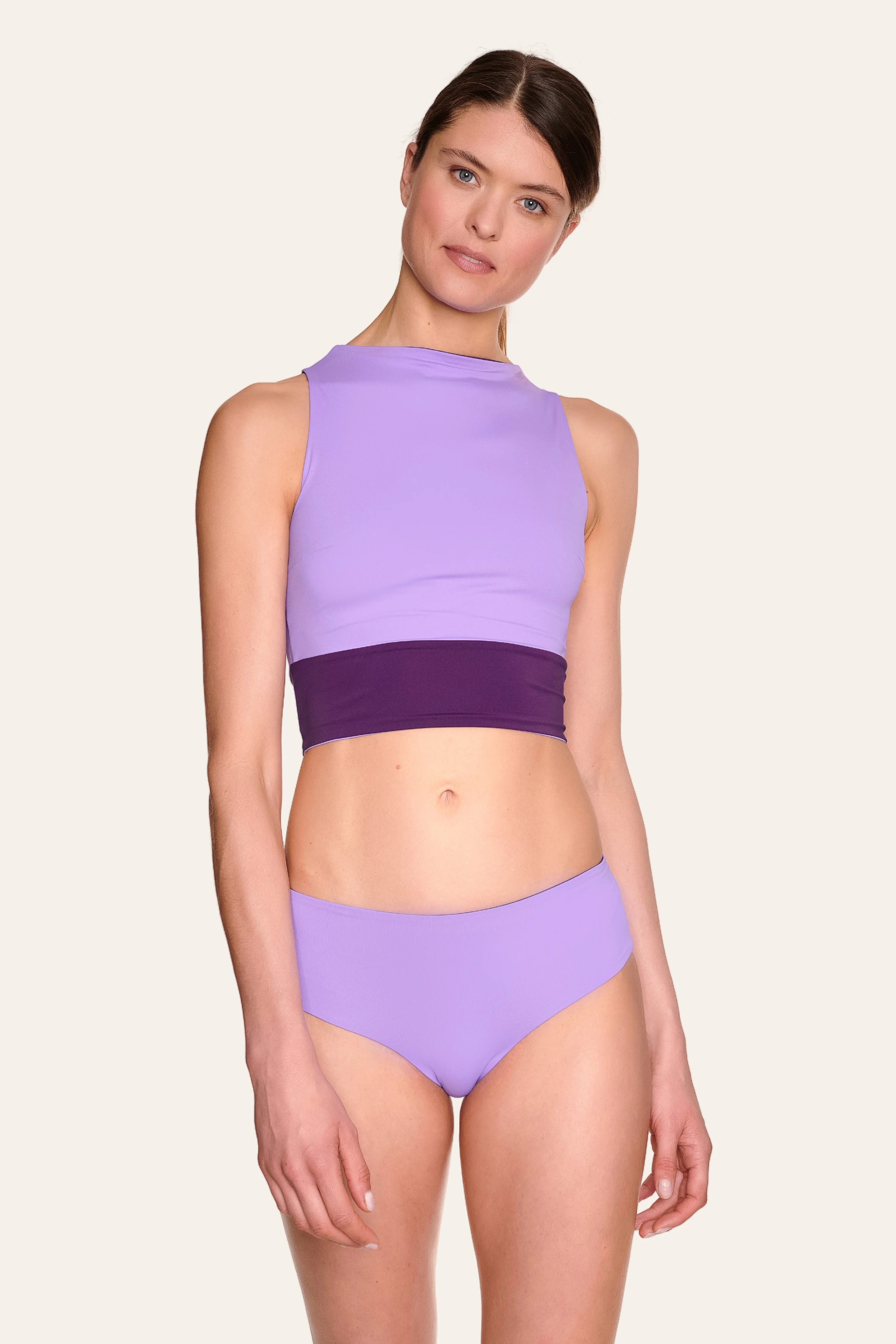 Frau trägt MYMARINI Bikini mit hochgeschlossenem Top und Mid-rise Hose in Lila.#color_lavender-plum