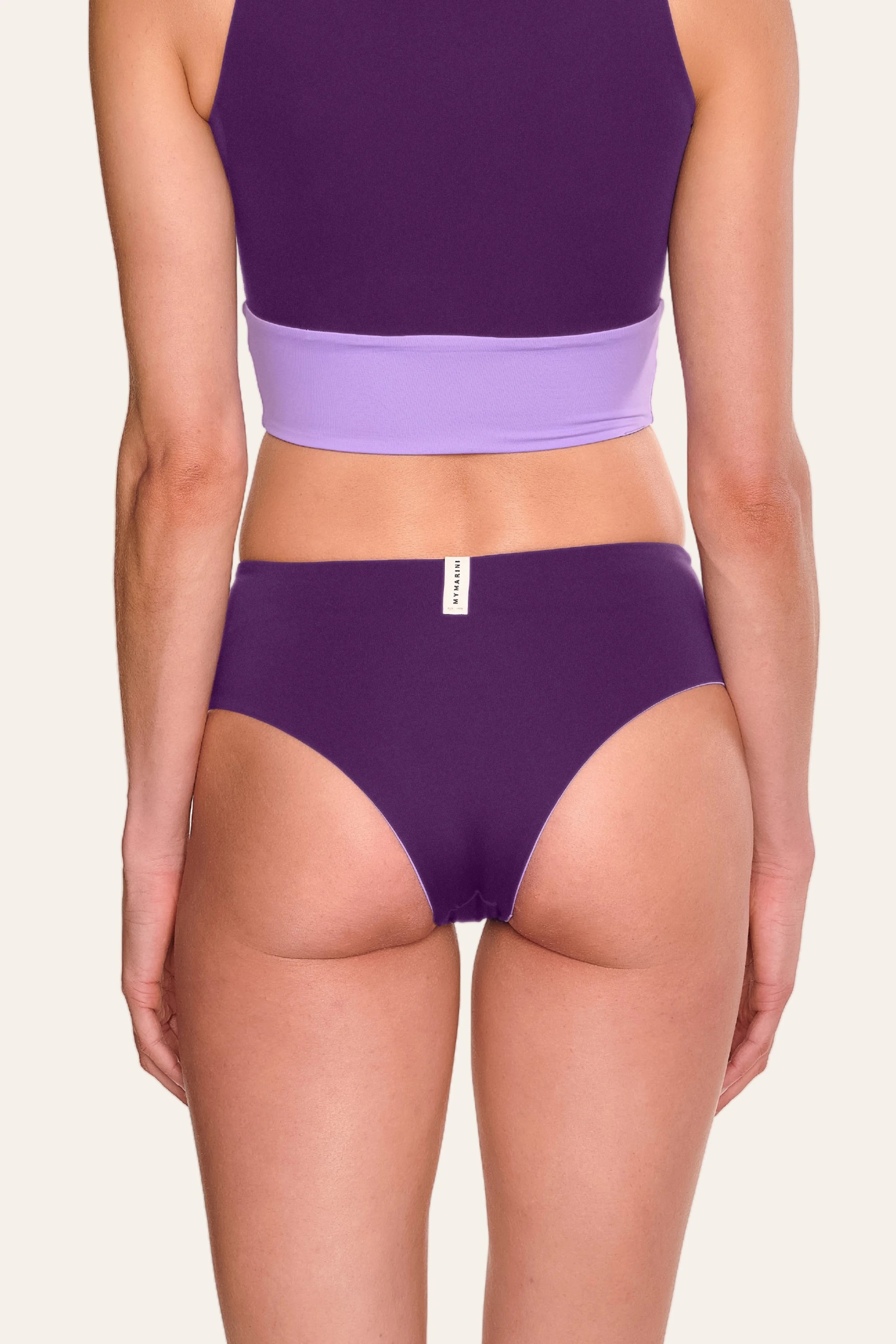 Rückansicht einer Person in lila MYMARINI Bikinihose mit hohem Beinausschnitt.#color_lavender-plum