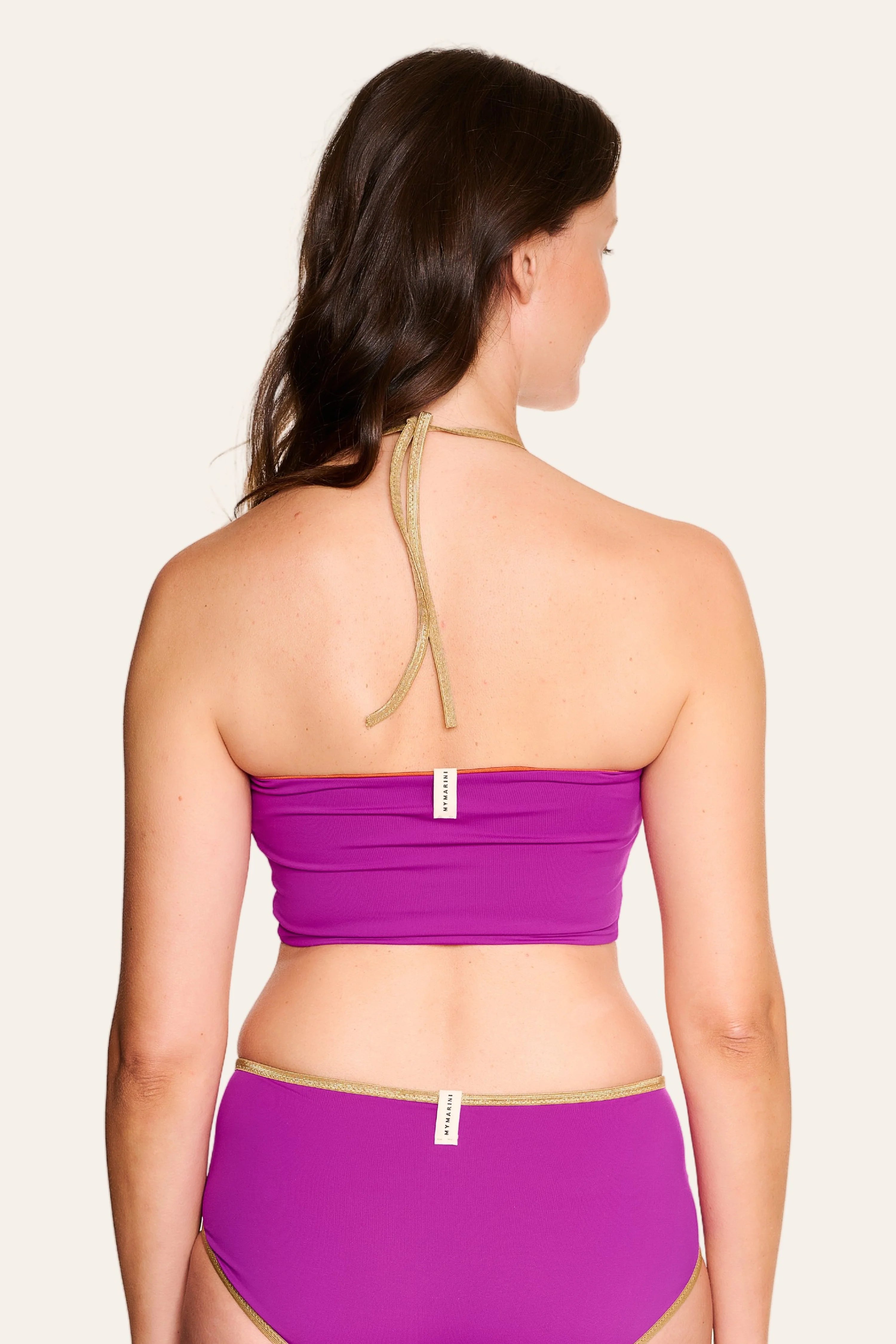 Frau in MYMARINI Bikini mit Neckholder und High Waist Schnitt in Lila, von hinten fotografiert.#color_papaya-cassis
