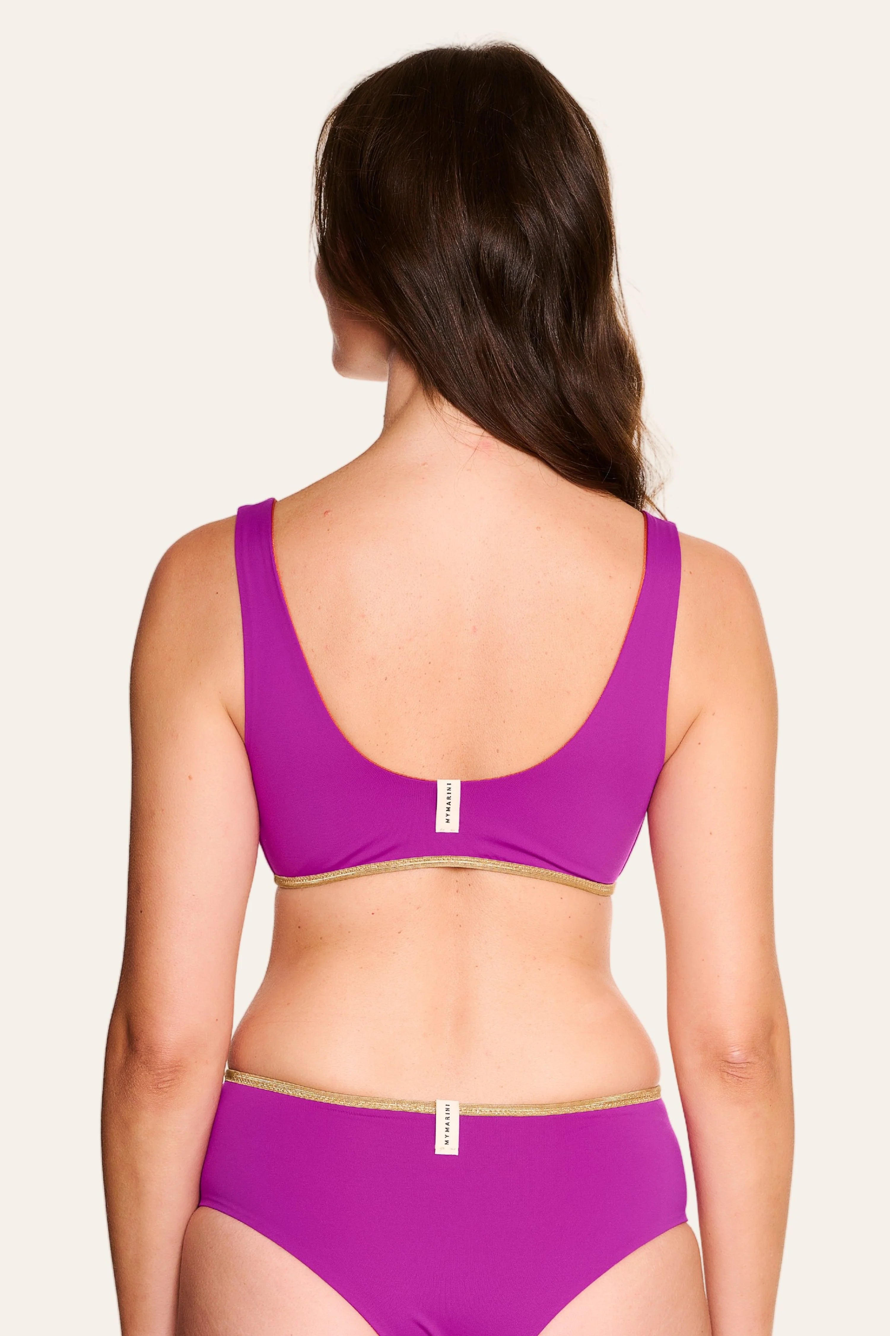 Frau trägt MYMARINI Bikini mit breiten Trägern und tiefem Rückenausschnitt in Lila.#color_papaya-cassis