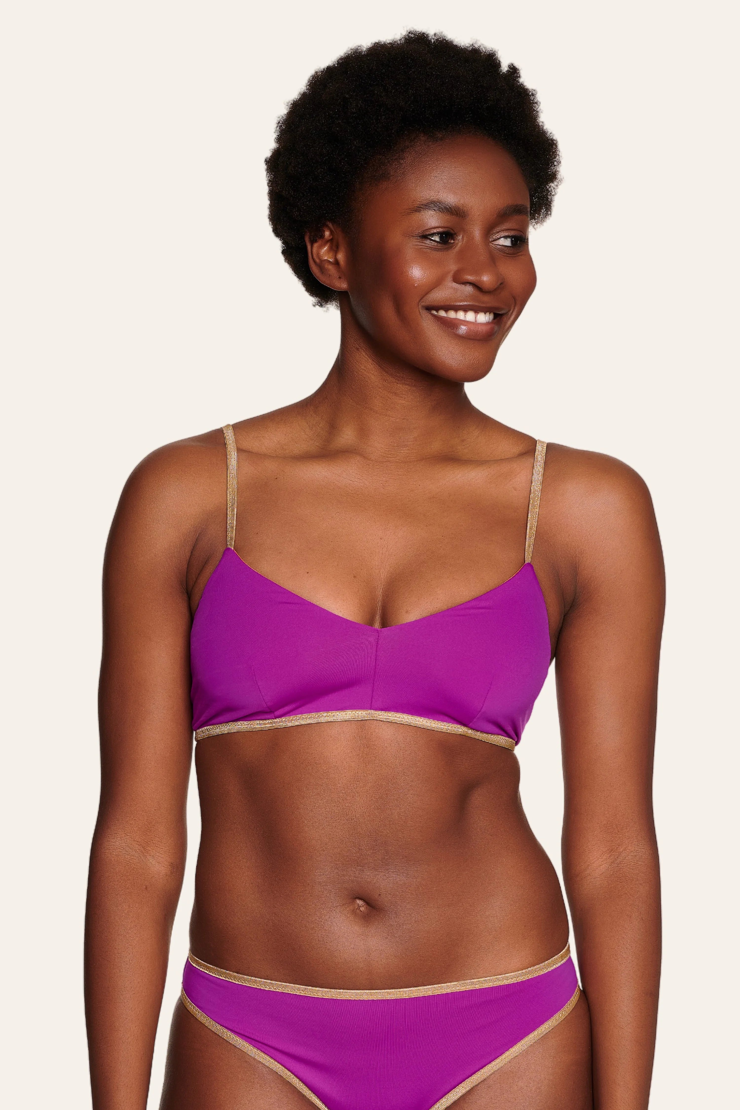 Frau trägt MYMARINI Bikinitop mit Spaghettiträgern und Bikinihose in Lila.#color_papaya-cassis