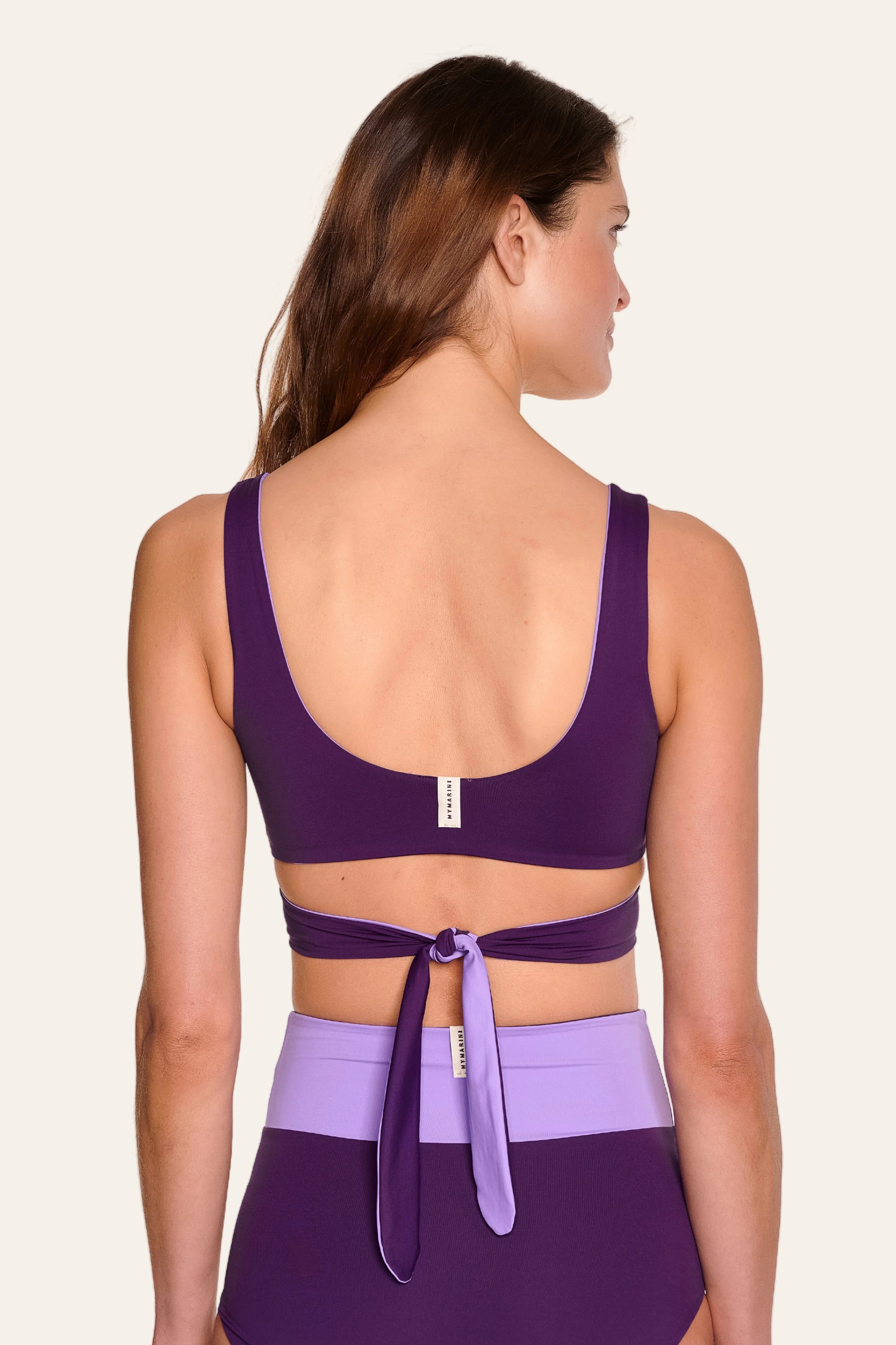Frau trägt MYMARINI Bikinitop mit tiefem Rückenausschnitt und breite Träger, kombiniert mit High-Waist-Bikinihose.#color_lavender-plum