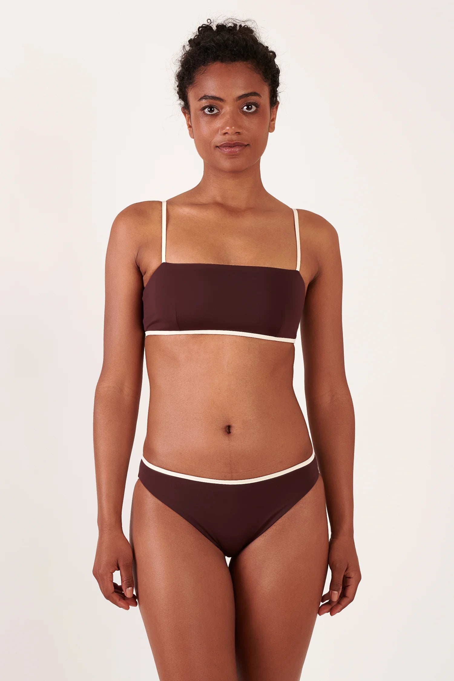 MYMARINI Bikini, Top: Bandeau mit dünnen Trägern, Hose: Mid Rise, braun mit weißem Rand, frontal posierende Person.#color_chocolate-lilac