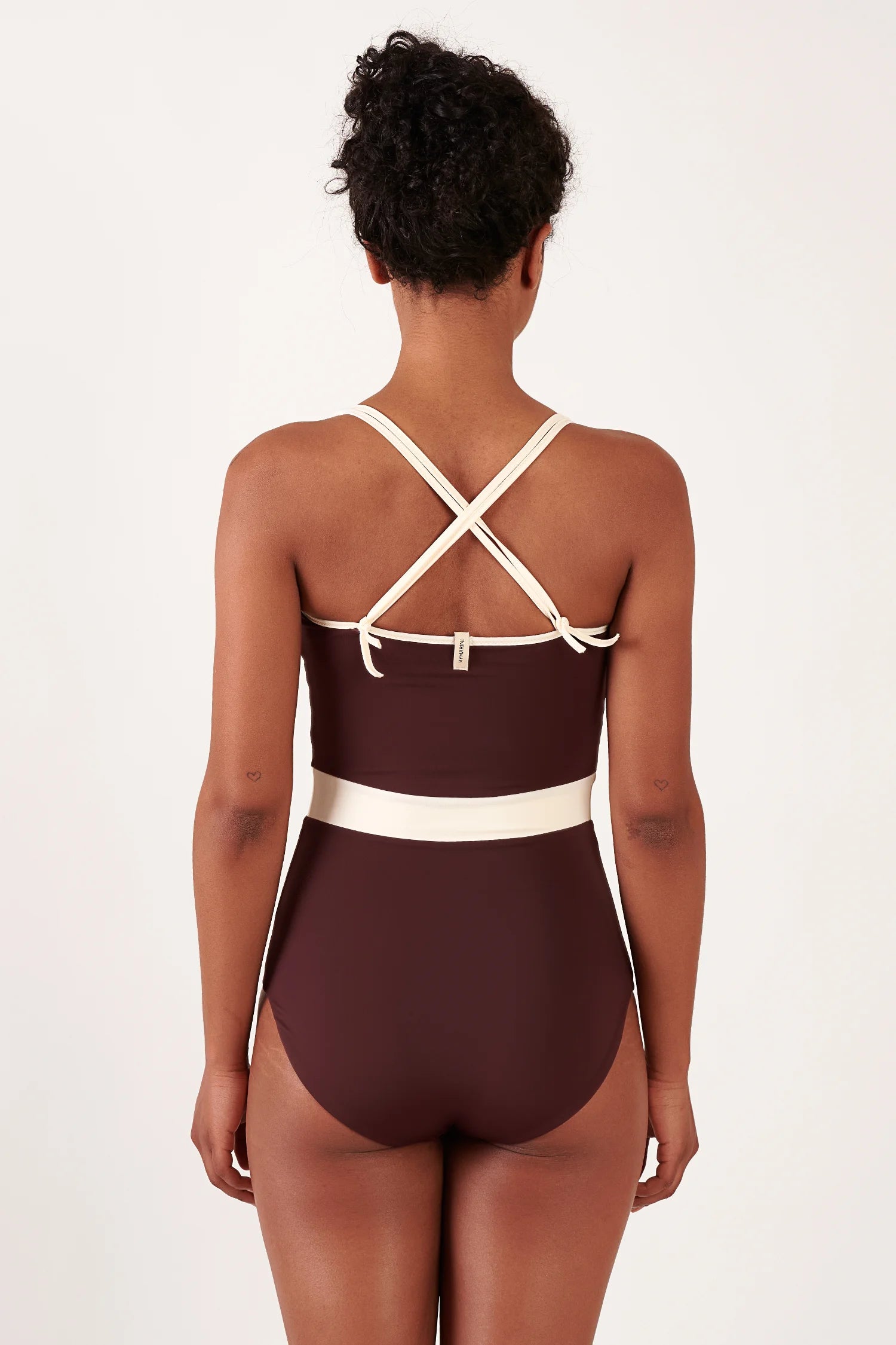 MYMARINI Badeanzug in Dunkelbraun, Rückenansicht mit kreuzenden Trägern, helles Taillenband aus Stoff.#color_chocolate-lilac