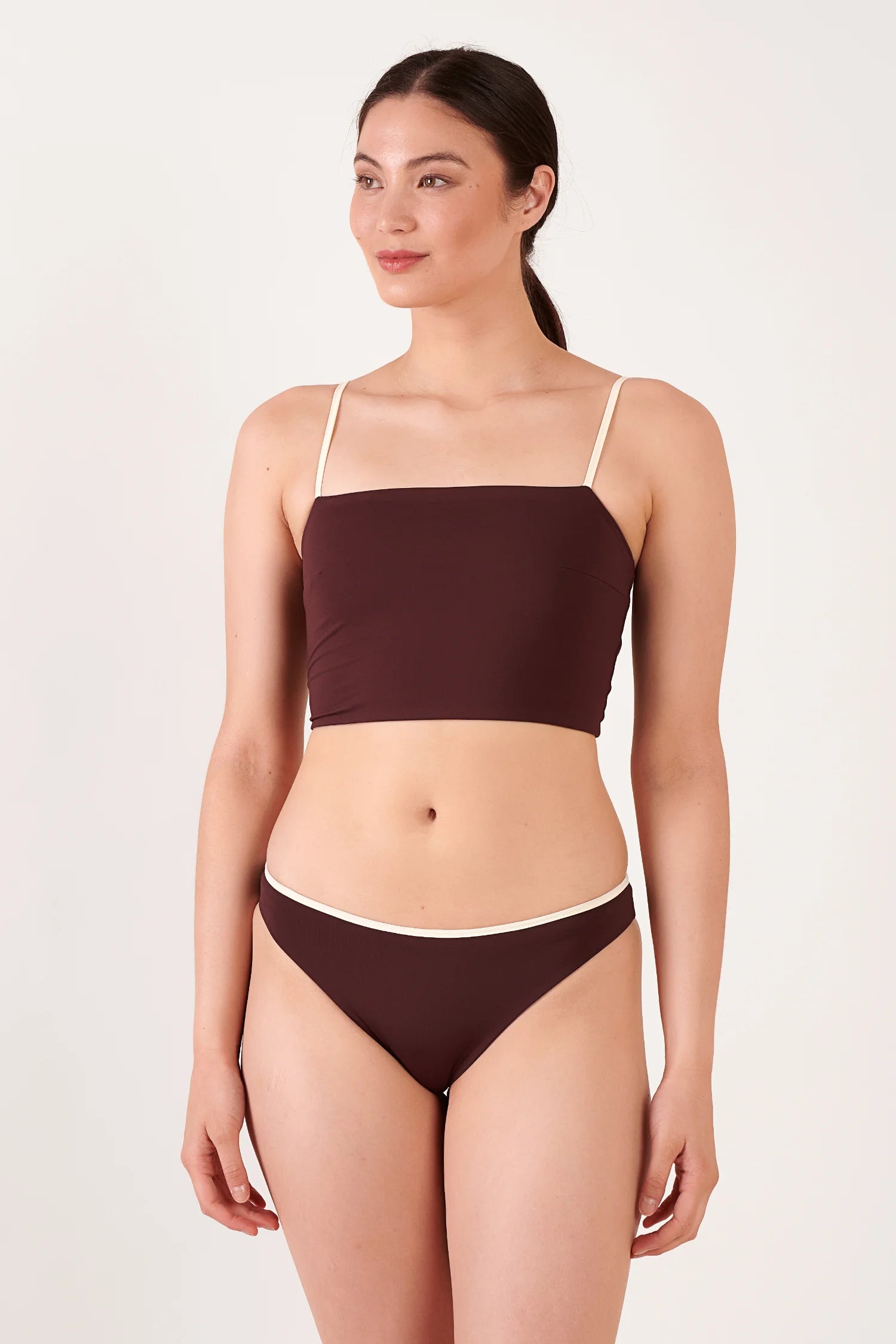 MYMARINI Bikini-Top braun mit weißen Spaghettiträgern, Bandeau-Schnitt; passende braune Bikini-Hose mit hellem Rand vor neutralem Hintergrund.#color_chocolate-lilac