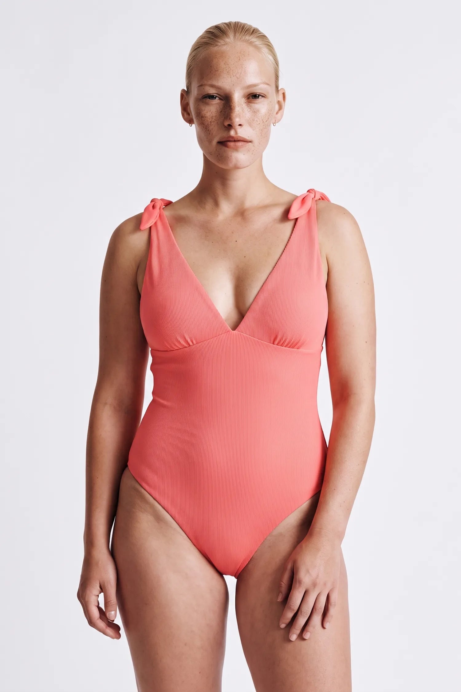 KI-generiert, Frau trägt MYMARINI BOW BODY Badeanzug in sorbet, tiefer V-Ausschnitt und Schulterschleifen#color_sorbet