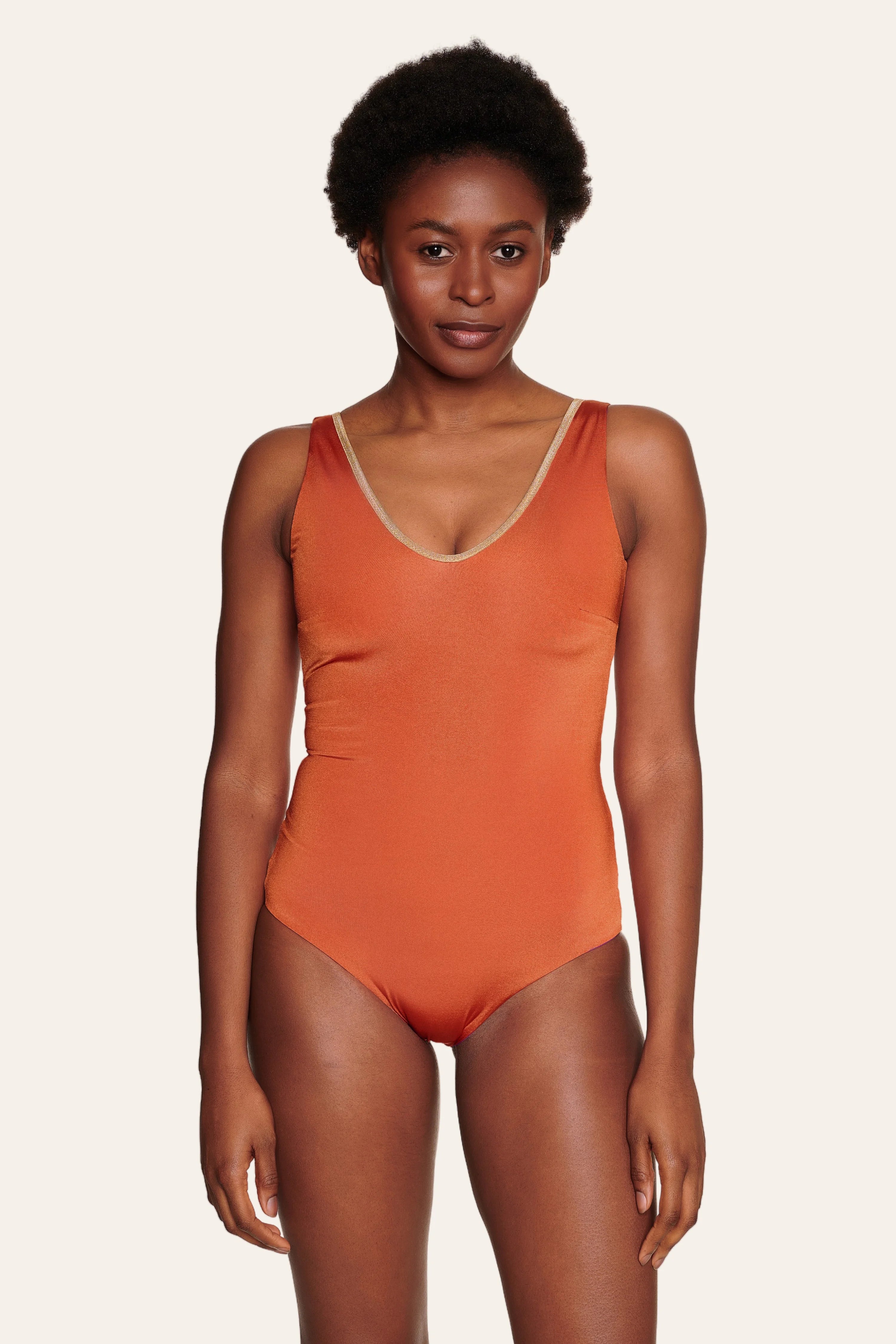 Frau trägt MYMARINI Badeanzug in Orange mit V-Ausschnitt und breiten Trägern.#color_papaya-cassis