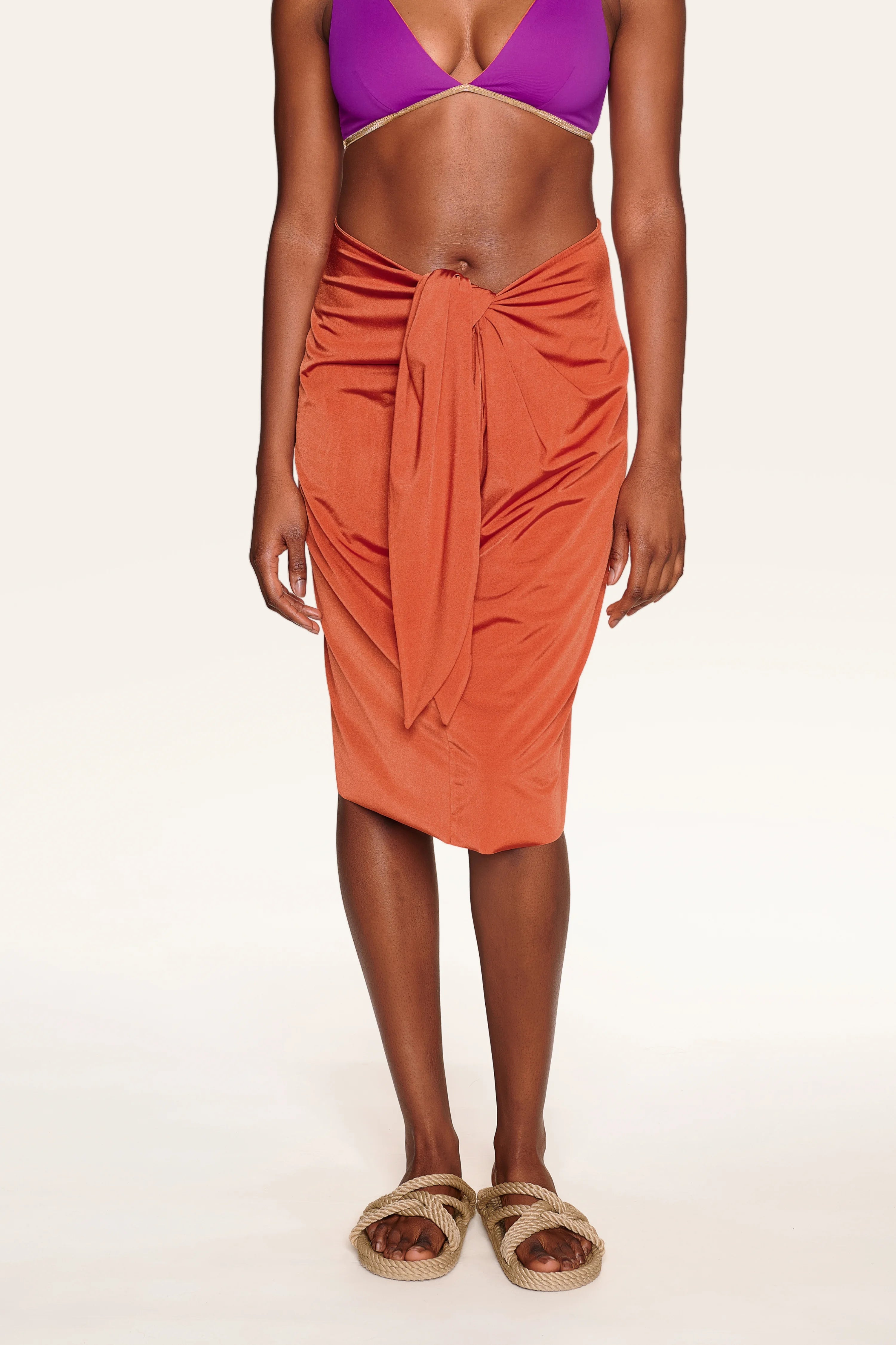 Person trägt ein lila Bikinitop mit Spaghettiträgern von MYMARINI und einen orangefarbenen Rock.#color_papaya