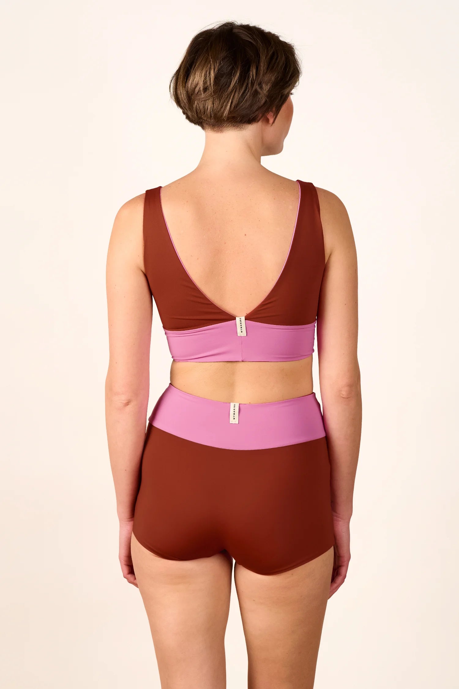 Frau in braunem MYMARINI-Bikinitop mit V-Ausschnitt und passender High-Waist-Bikinihose, Rückansicht.#color_sienna-orchid
