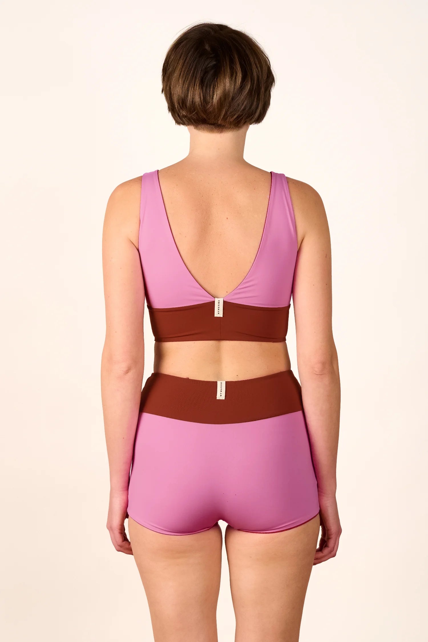 Person trägt MYMARINI Bikinitop mit V-Ausschnitt und Bikinihose mit hohem Bund in Rosa und Braun, Rückansicht.#color_sienna-orchid