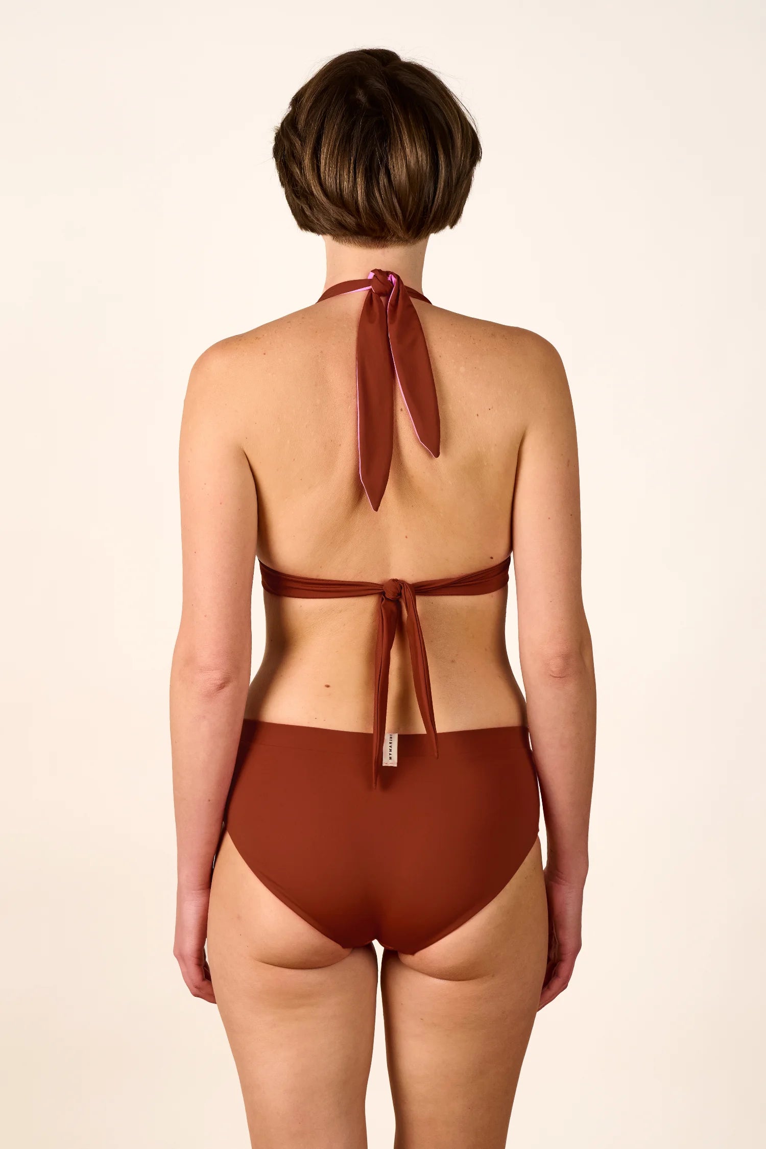 Rückansicht einer Person in einem MYMARINI Bikini mit Neckholder und hoher Taille, in warmem Braunton.#color_sienna-orchid