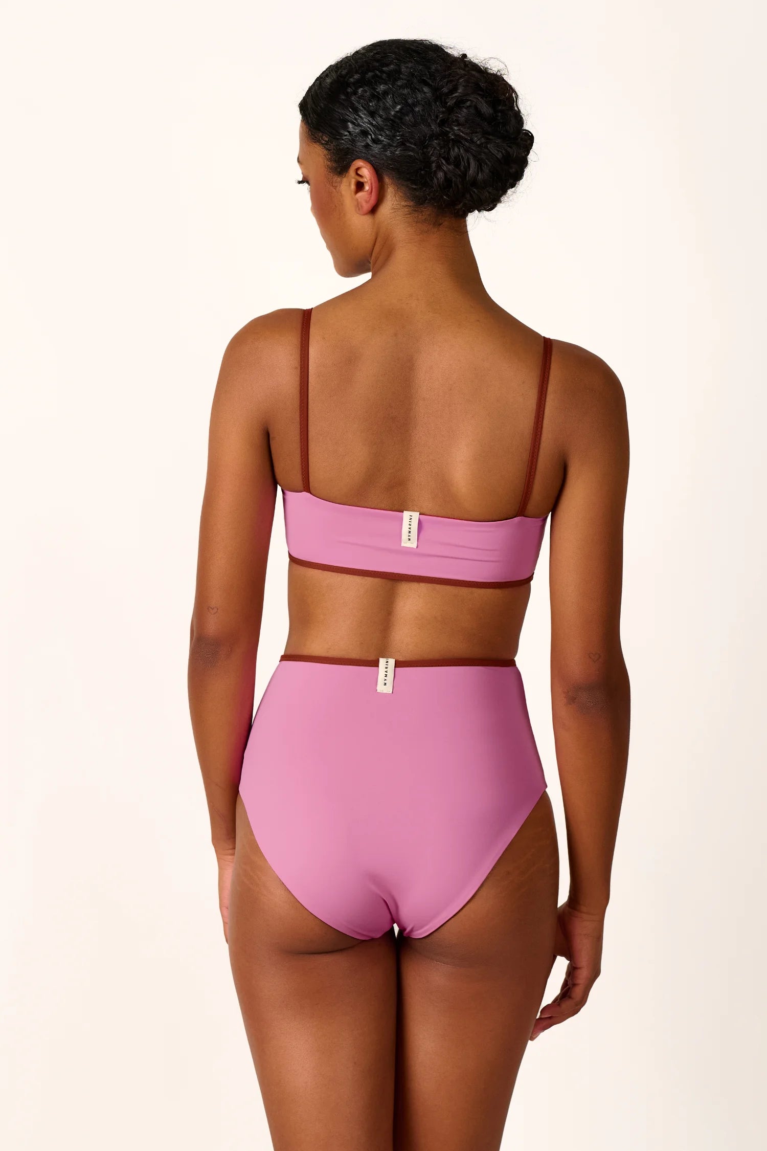 Frau trägt MYMARINI Bikini mit Spaghettiträgern und High-Waist-Schnitt in Rosa, Rückansicht.#color_sienna-orchid