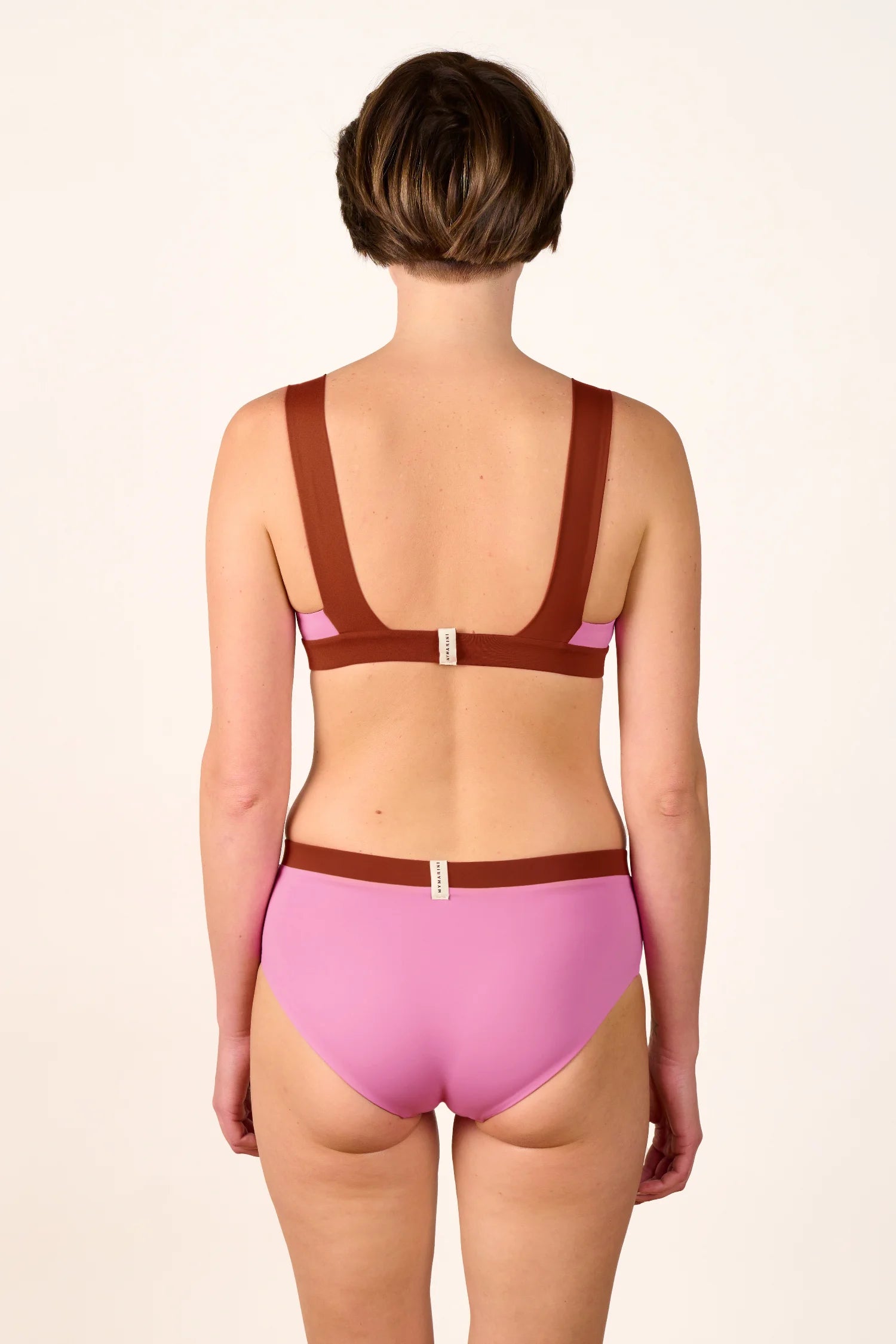 Rückansicht einer Frau in einem MYMARINI Bikinitop mit breiten Trägern und Bikinihose in Rosa und Braun.#color_sienna-orchid