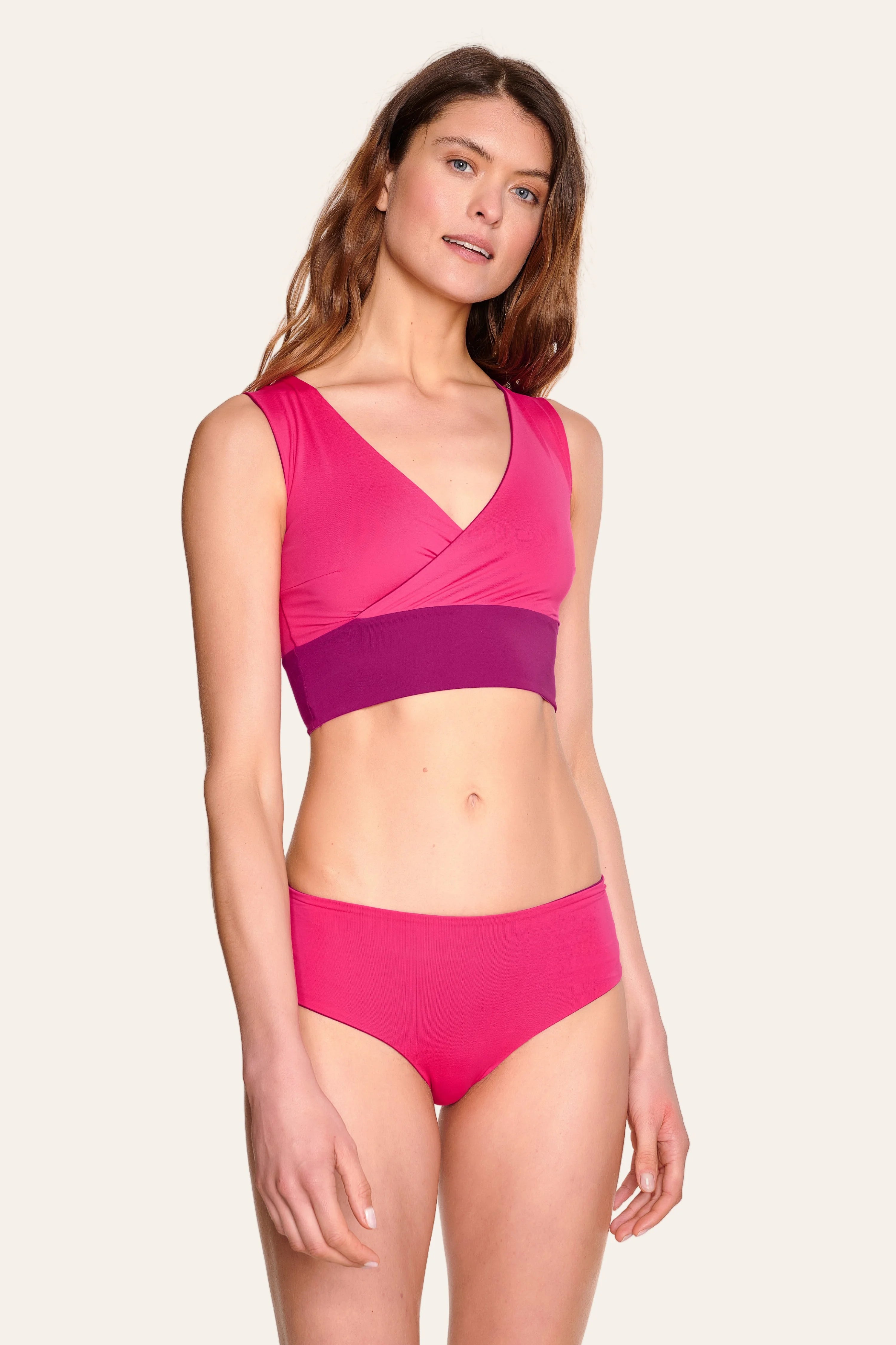 Frau trägt MYMARINI Bikinitop mit V-Ausschnitt und breite Träger, kombiniert mit passender Bikinihose.#color_pink-hortensia
