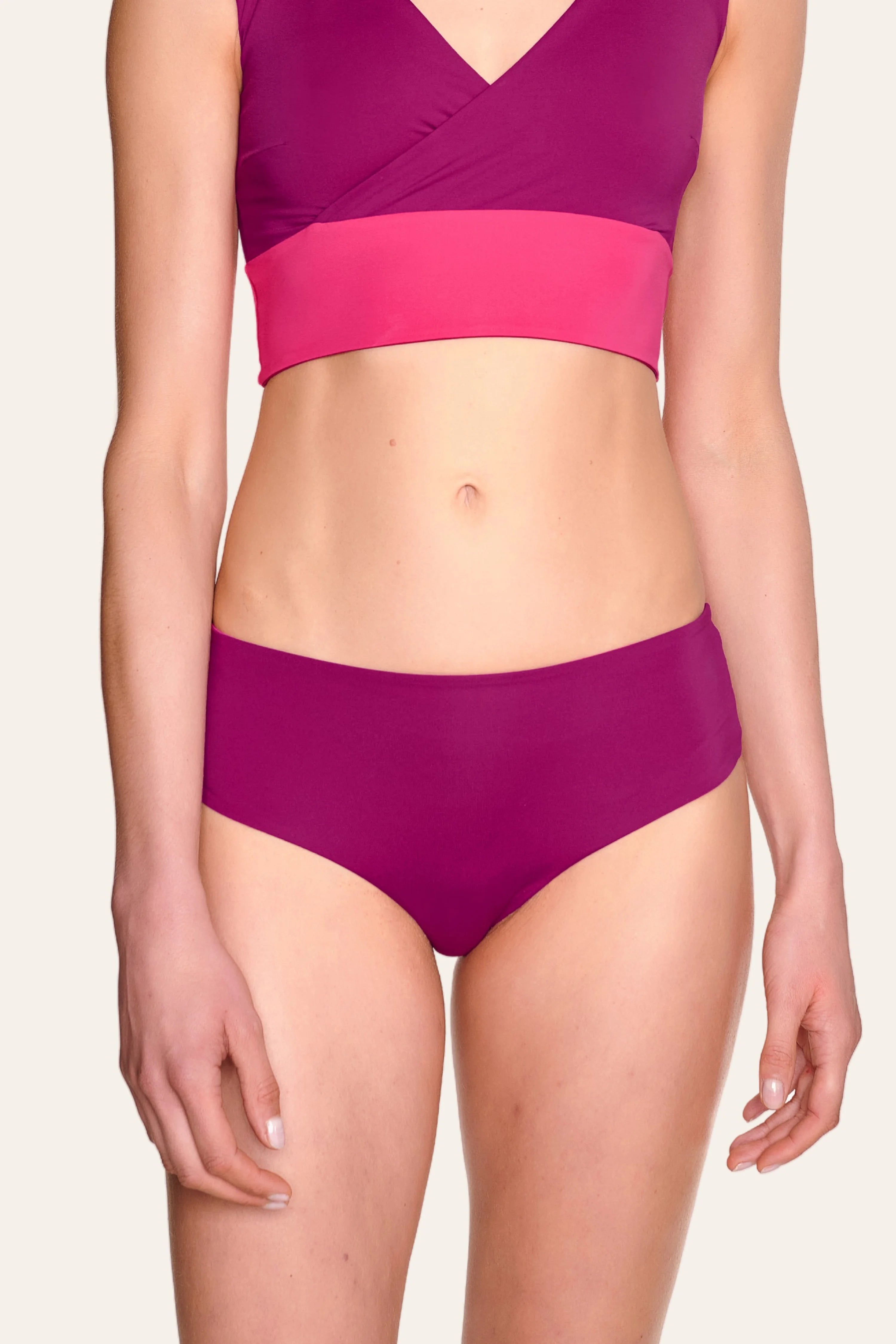 Frau trägt MYMARINI Bikinitop mit V-Ausschnitt und Bikinihose mit hohem Beinausschnitt in Pink- und Violetttönen.#color_pink-hortensia