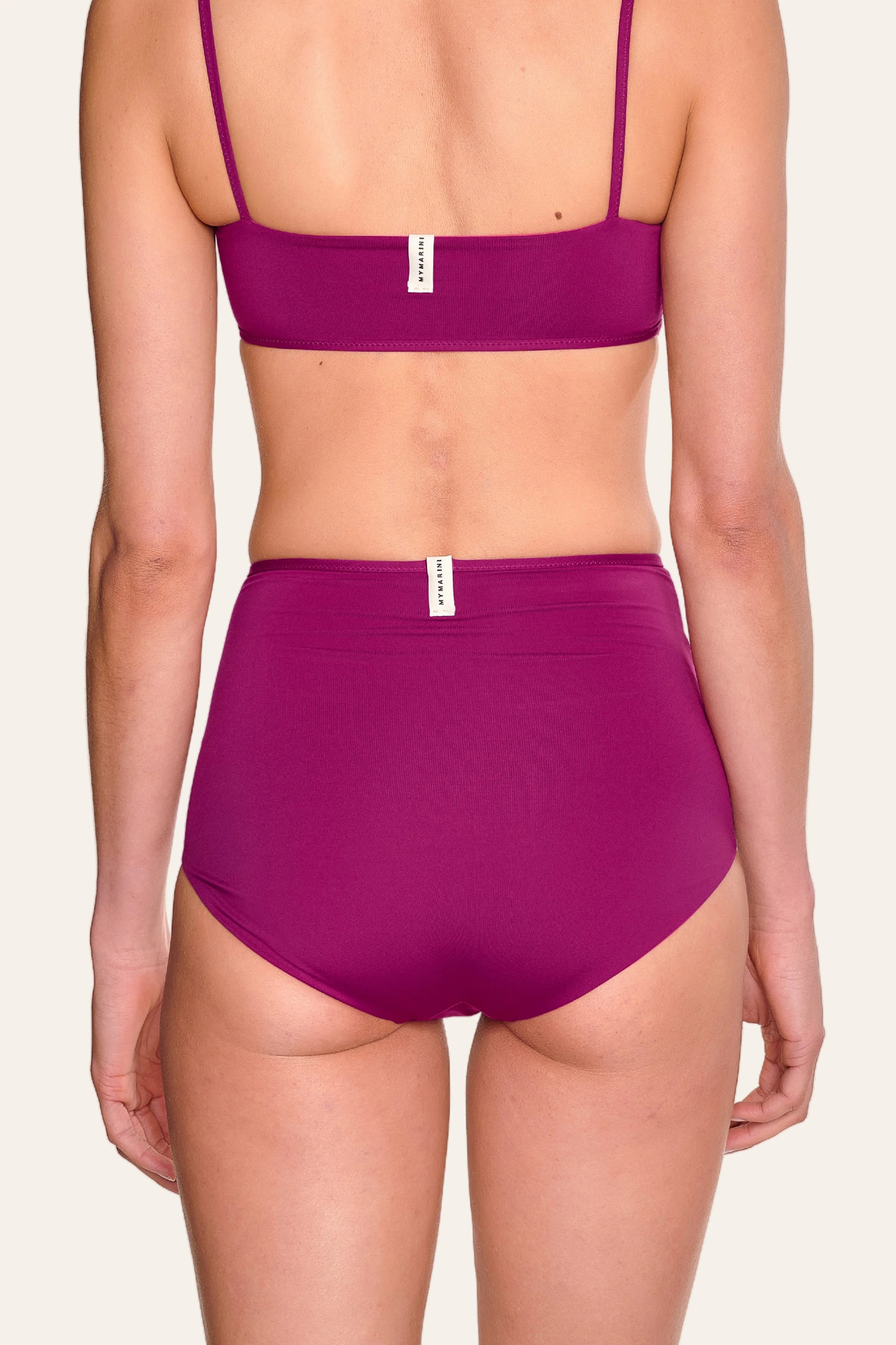Rückansicht einer Person in MYMARINI Bikinihose mit hohem Bund und Spaghettiträger-Bikinitop in Lila.#color_pink-hortensia