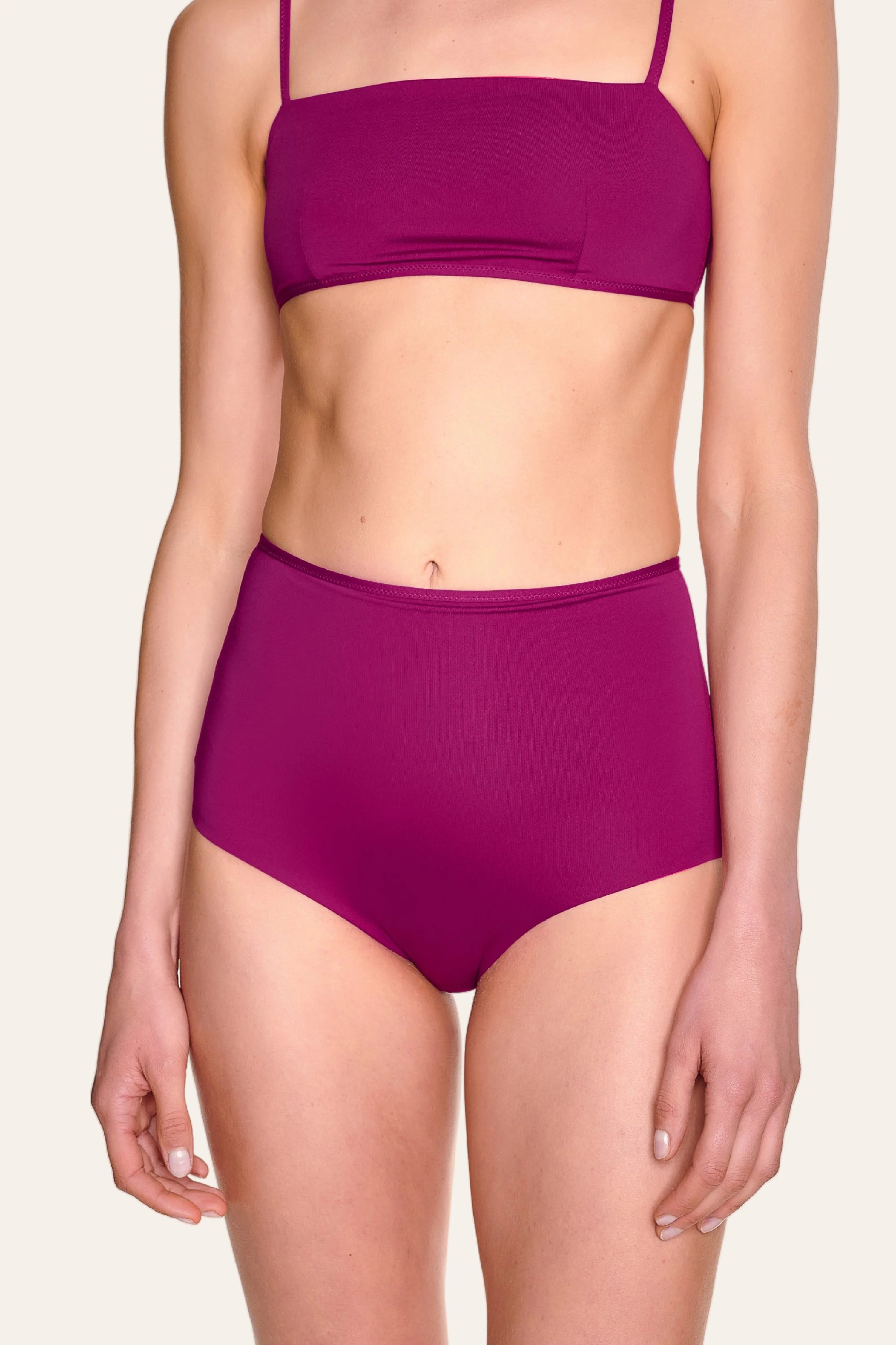 Frau trägt MYMARINI Bikini mit Bandeau-Top und hoch geschnittener Bikinihose in kräftigem Pink.#color_pink-hortensia