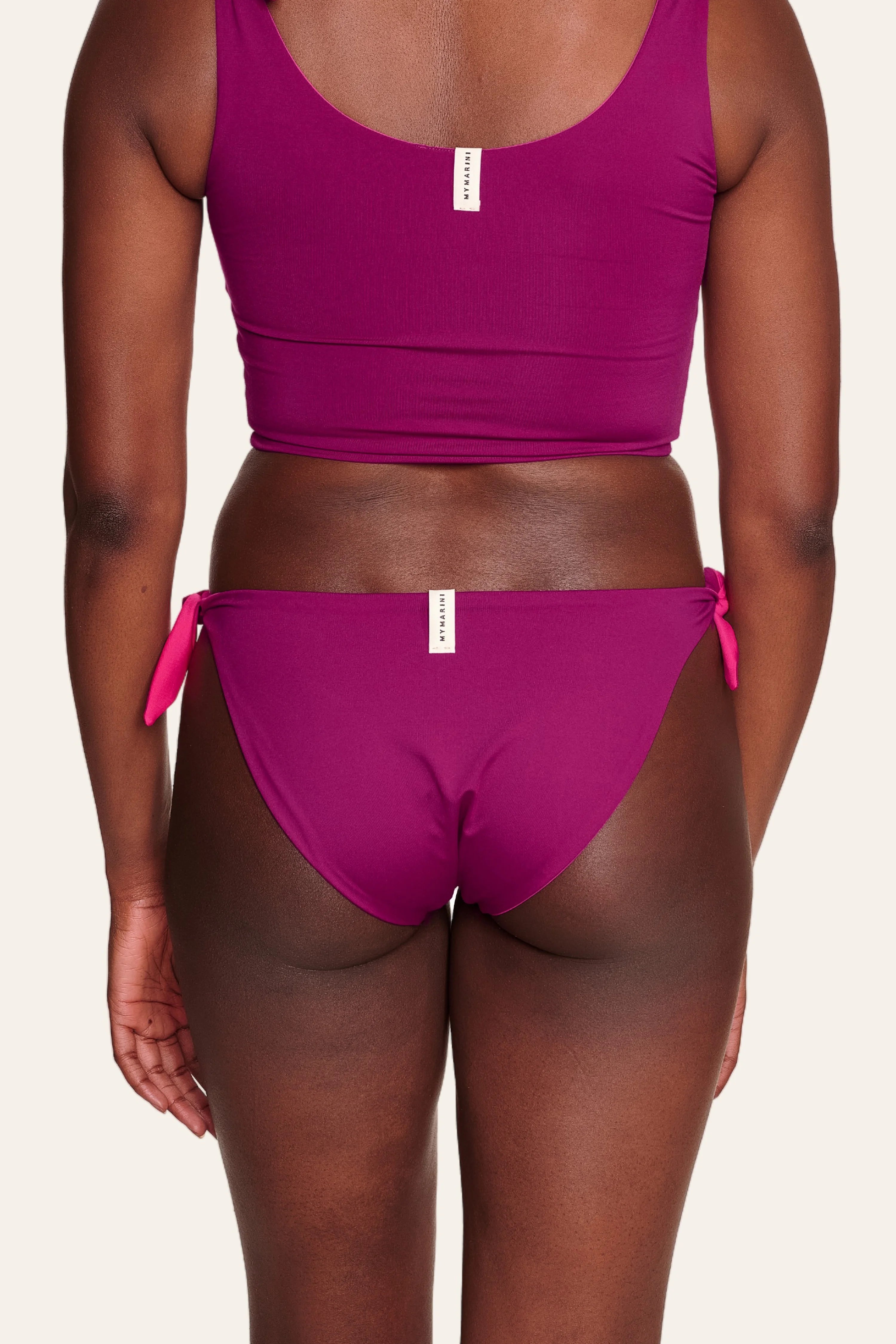 Frau in MYMARINI Bikinitop mit breiten Trägern und Bikinihose mit seitlichen Bändern, beide in kräftigem Pink, von hinten.#color_pink-hortensia