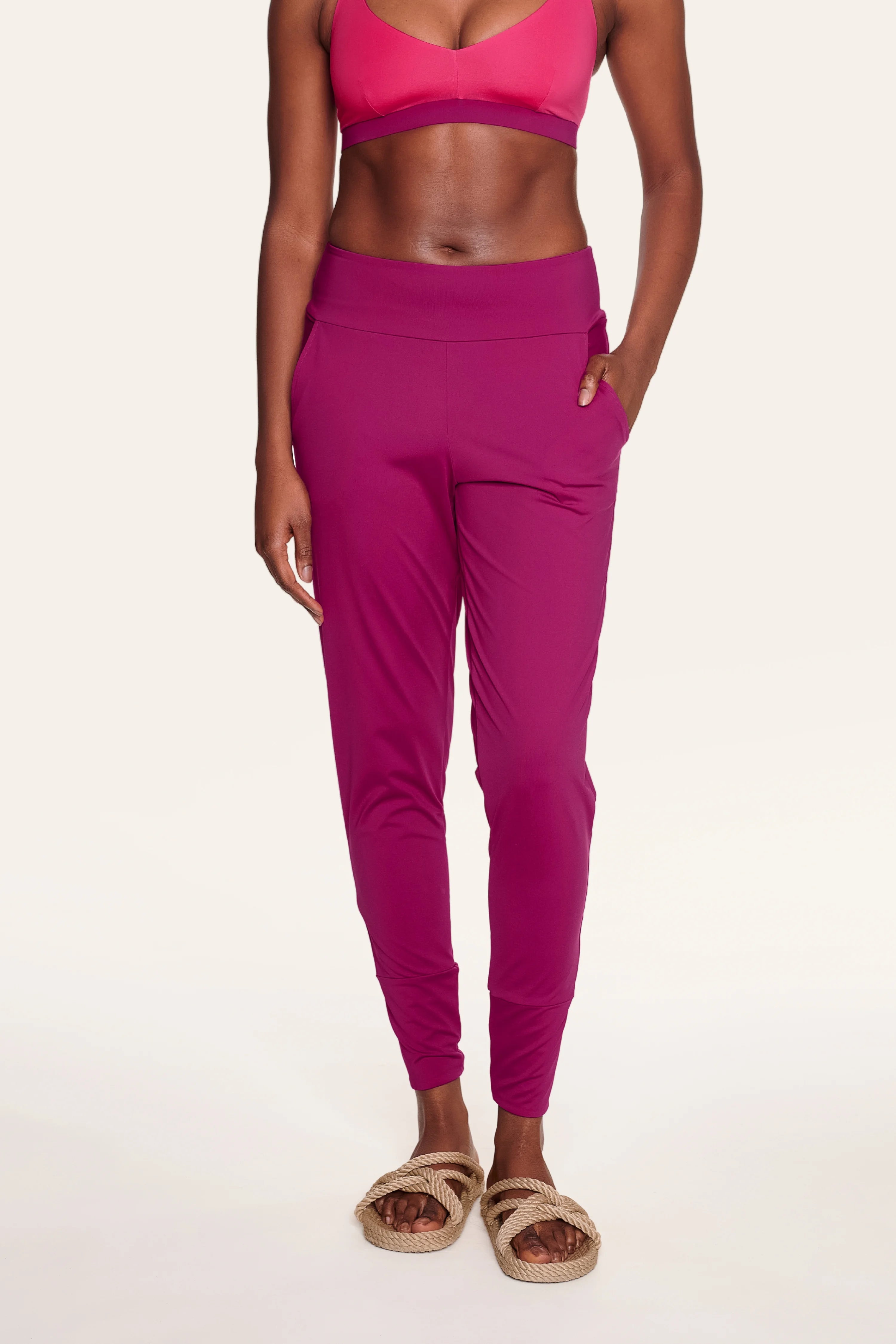 Person in pinkem MYMARINI-Bikinitop mit V-Ausschnitt und passender Hose, stehend, Hände in den Hosentaschen.#color_hortensia