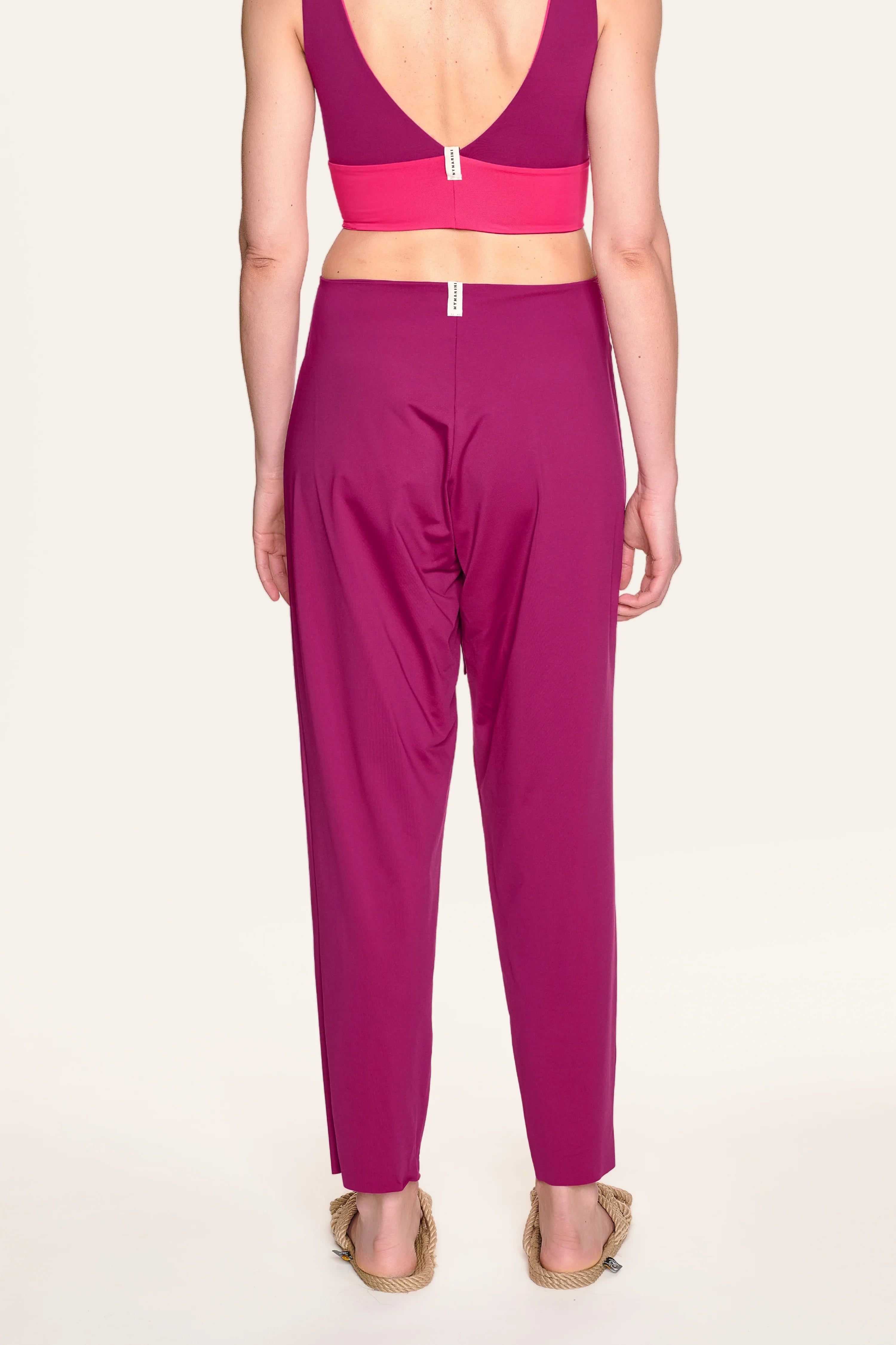 Rückansicht einer Person in MYMARINI Bikinitop mit tiefem Rückenausschnitt und Hose in kräftigem Pink.#color_hortensia
