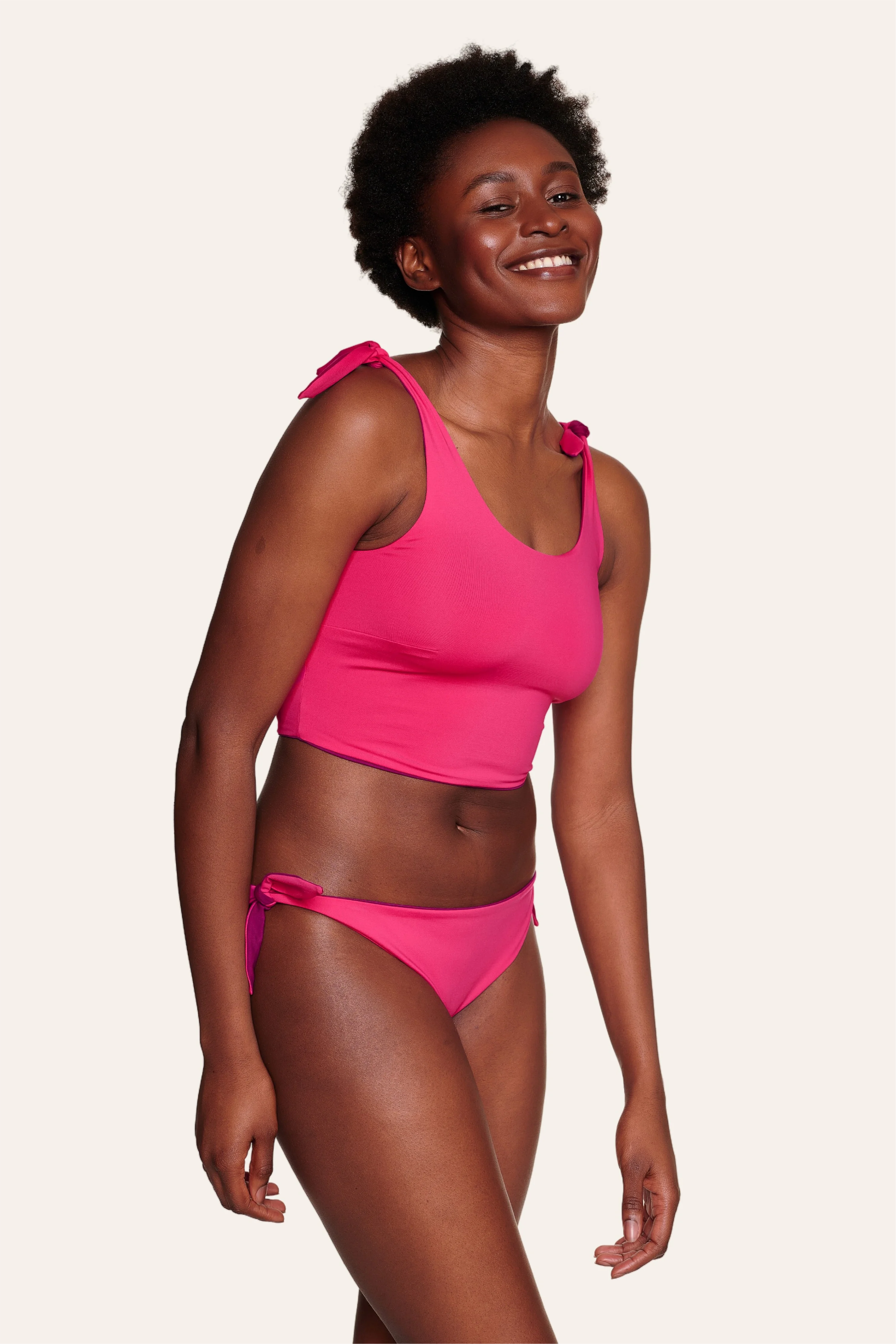 Frau trägt pinkes MYMARINI Bikinitop mit breiten Trägern und Bikinihose mit hohem Beinausschnitt, lächelnd.#color_pink-hortensia
