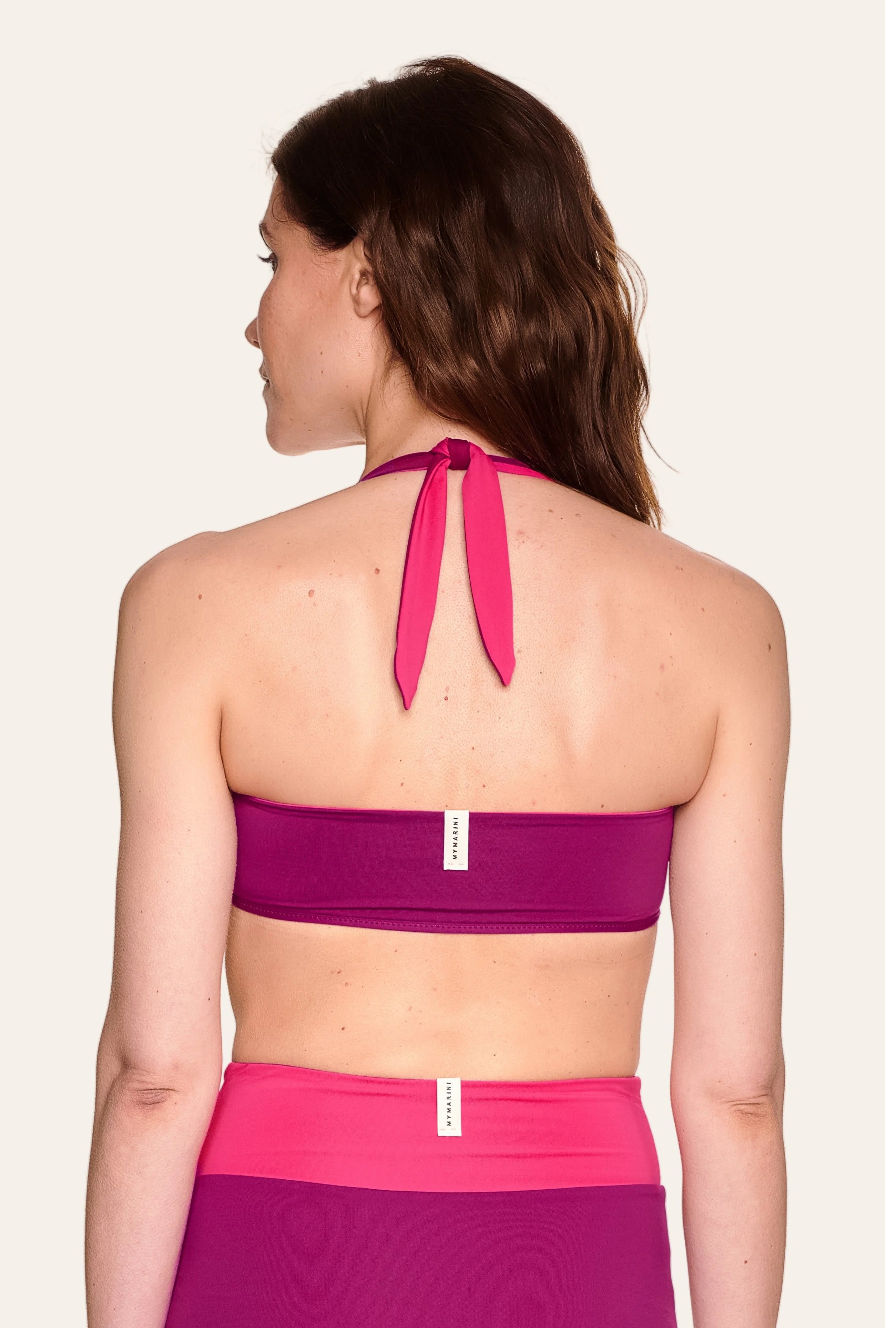 Frau von hinten in MYMARINI Neckholder-Bikinitop und High-Waist-Bikinihose in Pink- und Violetttönen.#color_pink-hortensia
