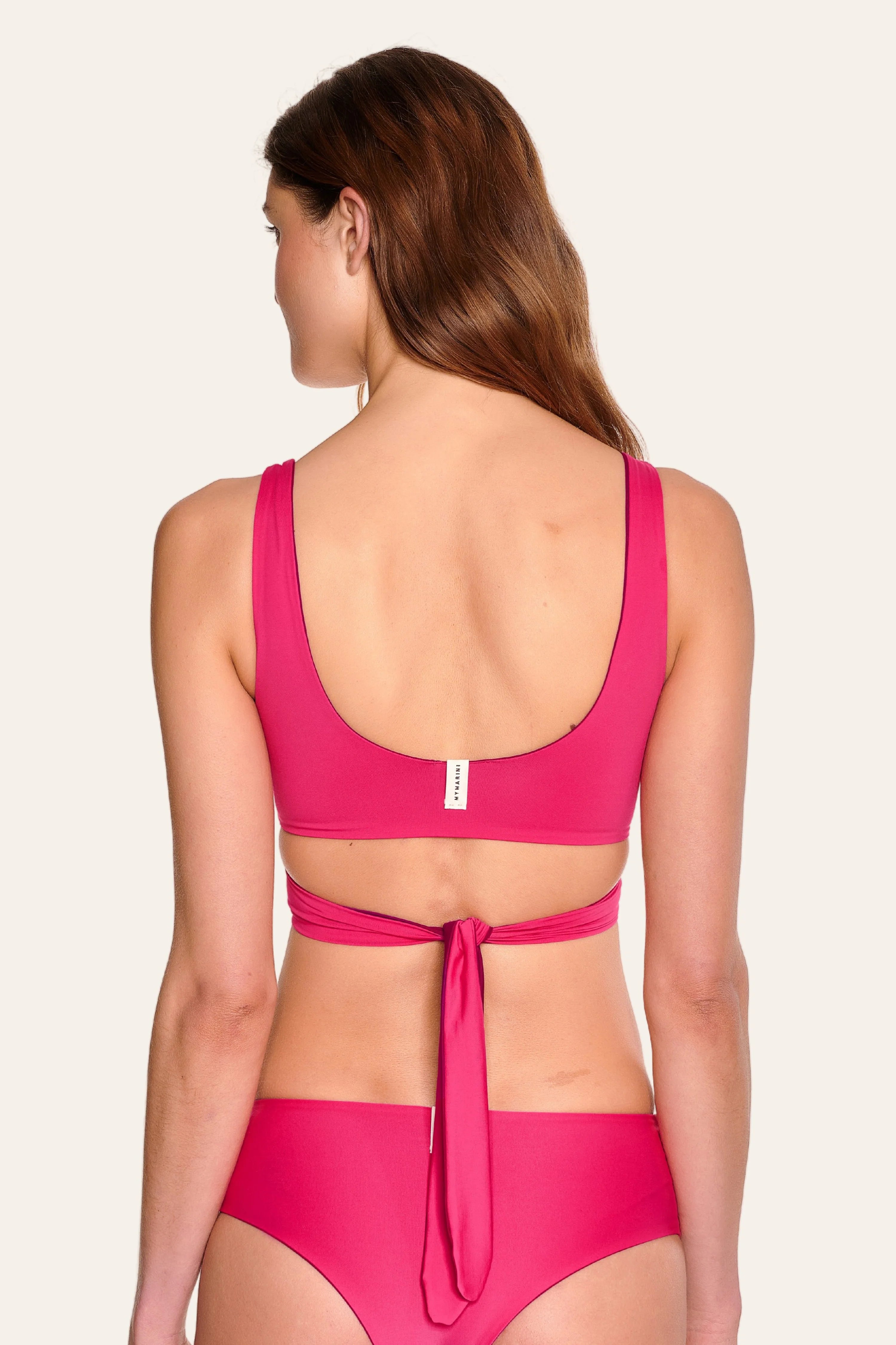 Frau in pinkem MYMARINI Bikinitop mit tiefem Rückenausschnitt und breiten Trägern, dazu passende Bikinihose.#color_pink-hortensia