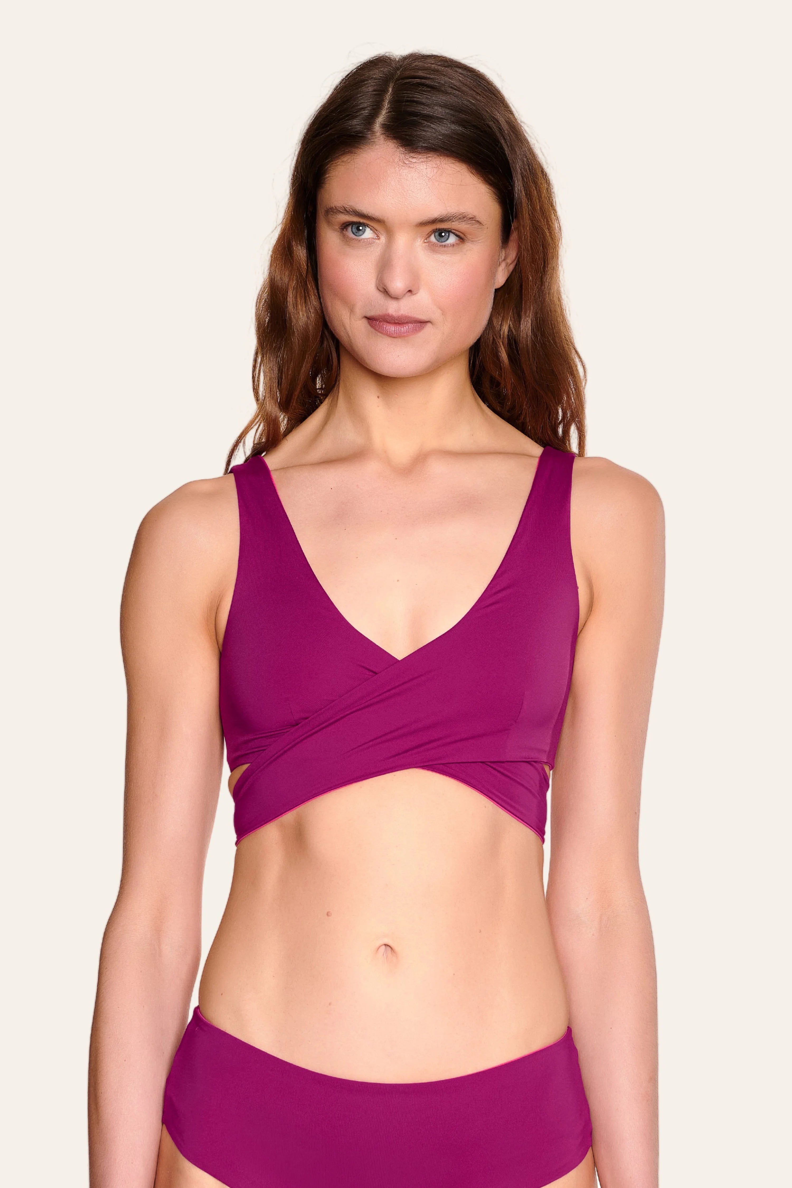 Frau trägt MYMARINI Bikinitop mit V-Ausschnitt und breiten Trägern in kräftigem Pink.#color_pink-hortensia