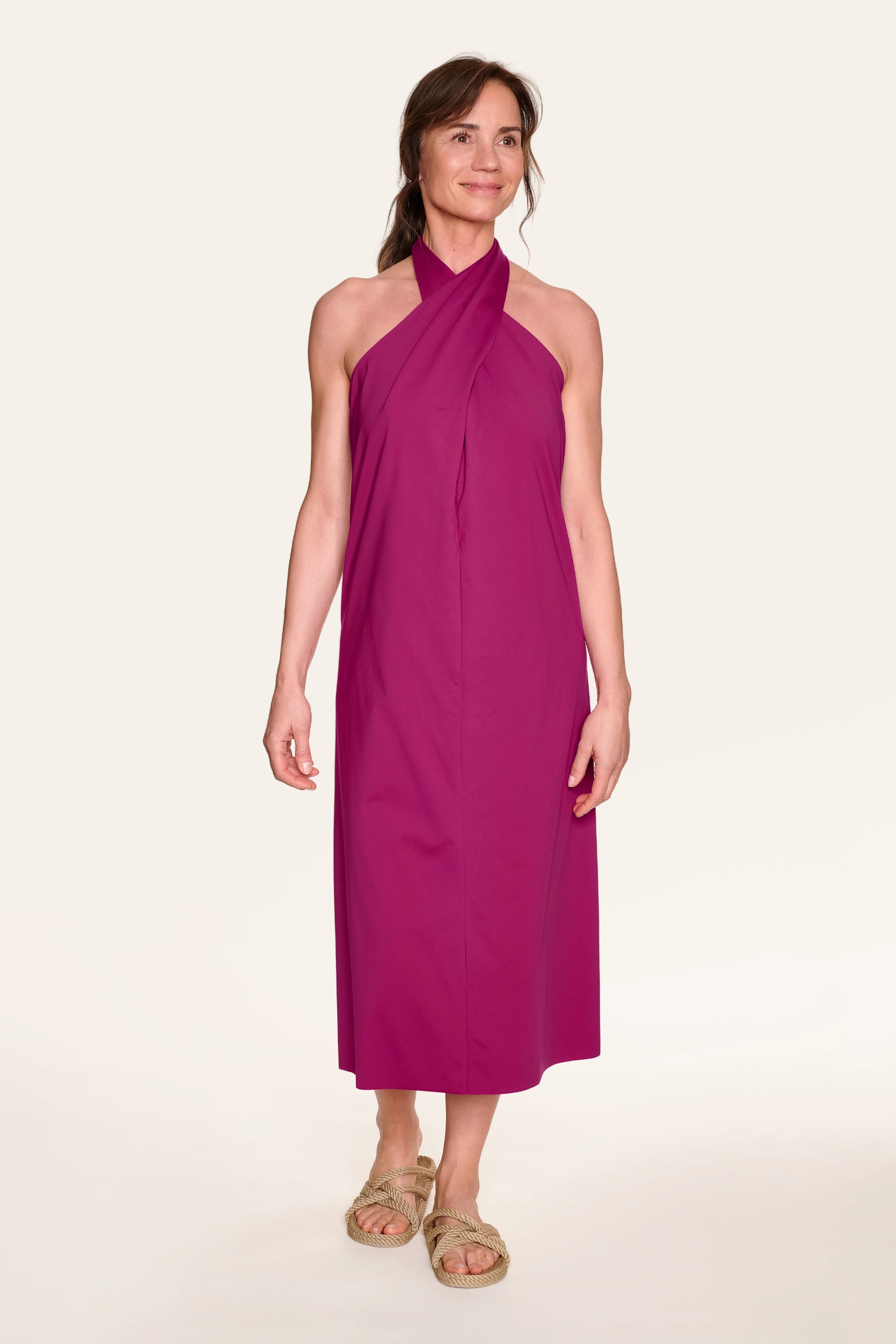 Frau trägt ein fuchsiafarbenes MYMARINI Neckholder-Kleid, lächelnd, mit Sandalen.#color_hortensia