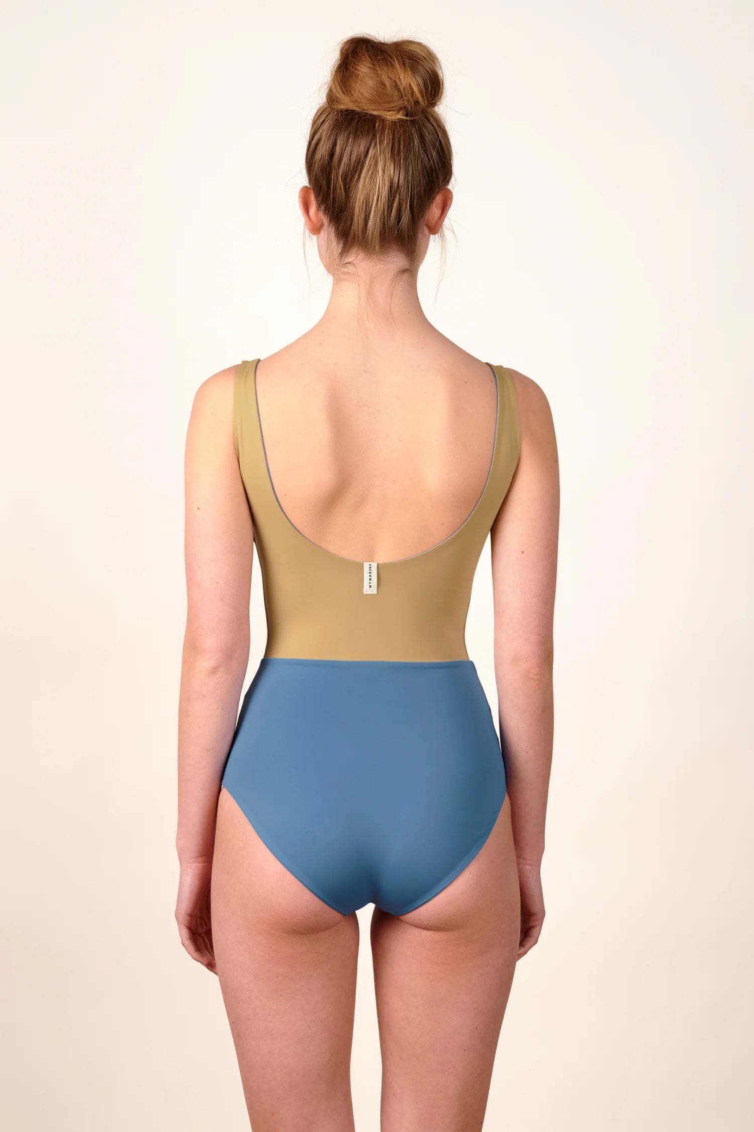 Rückenansicht eines MYMARINI Badeanzugs mit tiefem Rückenausschnitt und hohem Beinausschnitt in Beige und Blau.#color_coast-desert