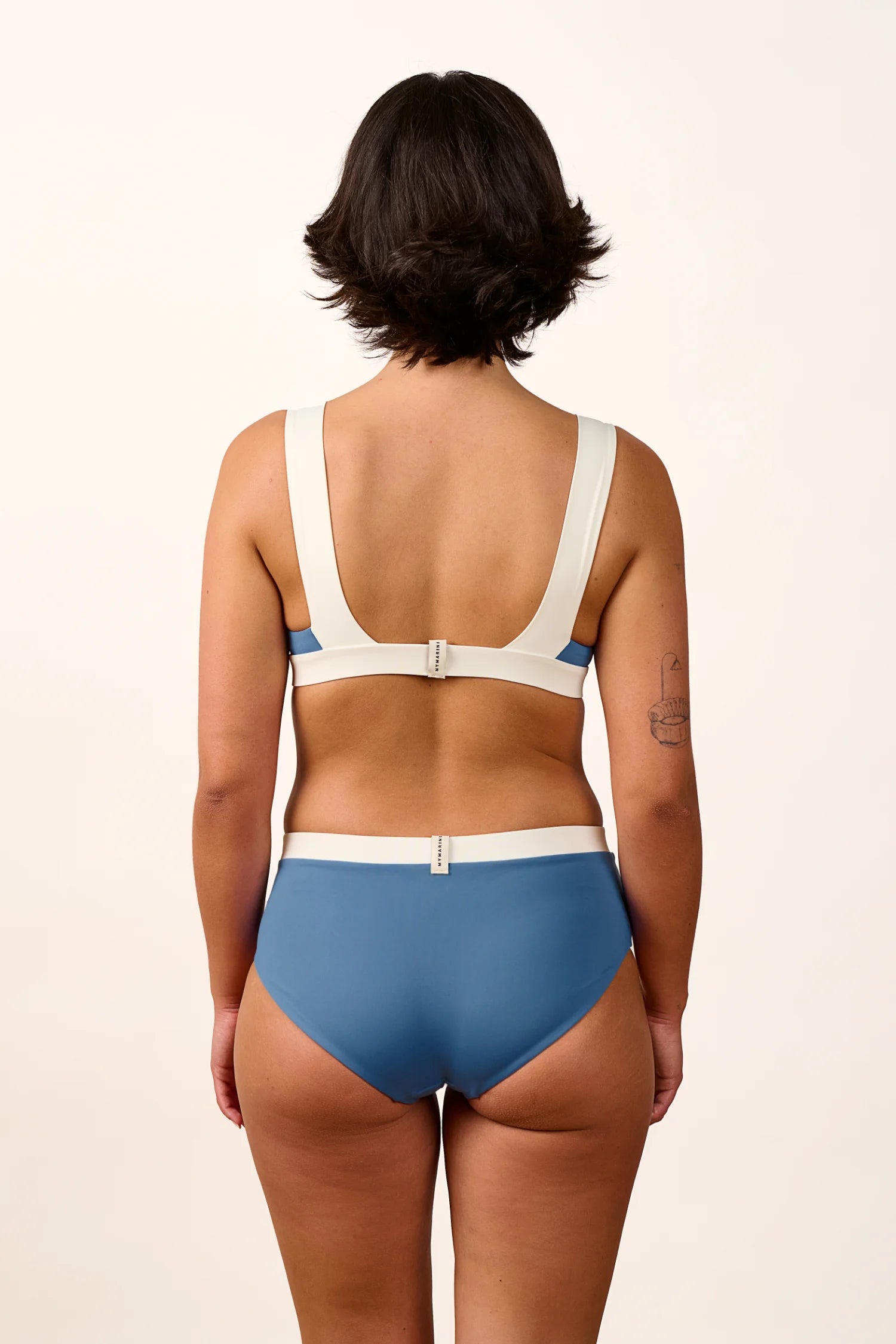 Rückansicht einer Frau in einem MYMARINI Bikini mit breiten Trägern und High-Waist-Schnitt in Blau und Weiß.#color_coast-desert