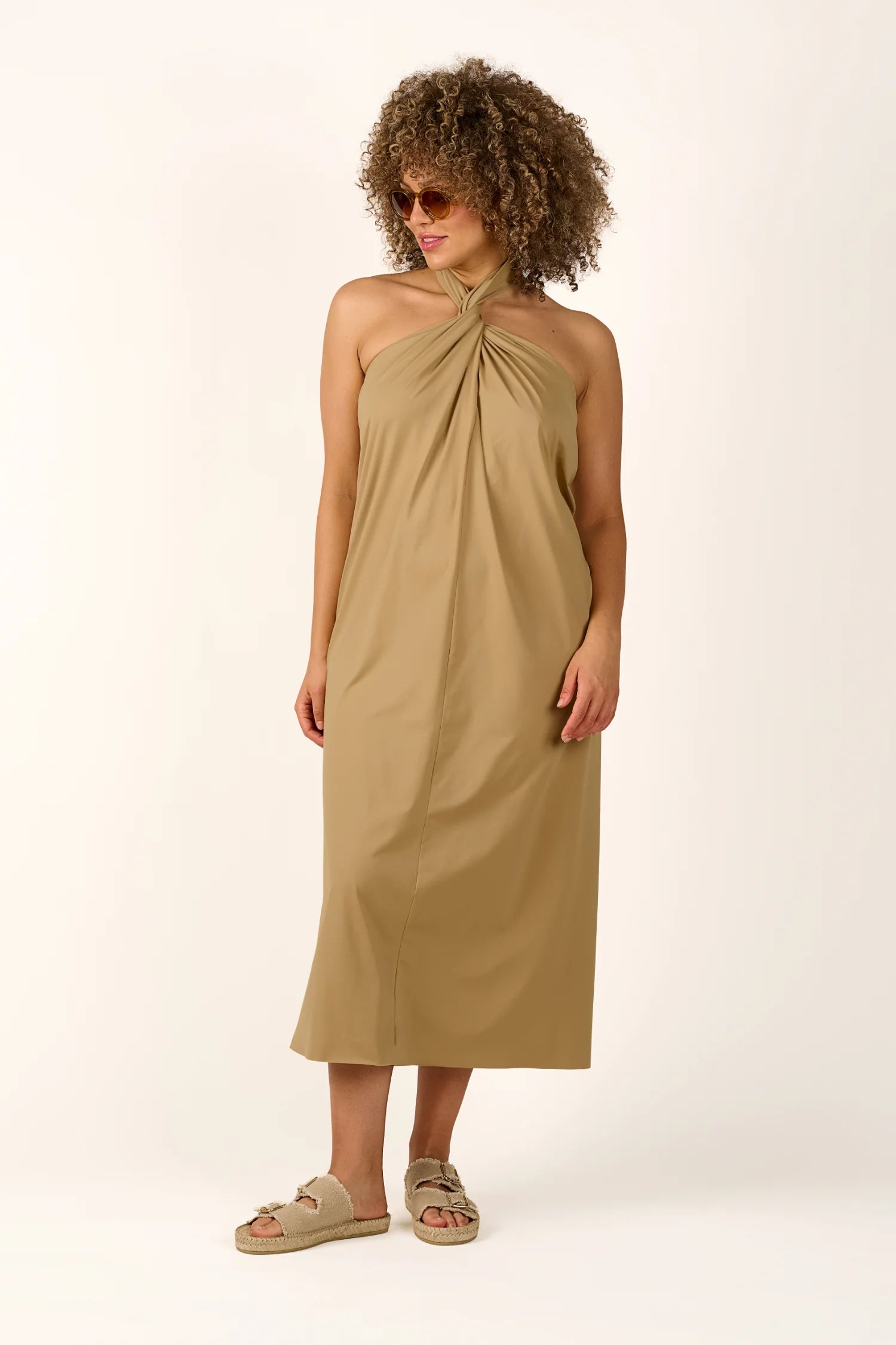 Person trägt ein MYMARINI Neckholder-Kleid in Beige, knielang, mit Sandalen.#color_desert