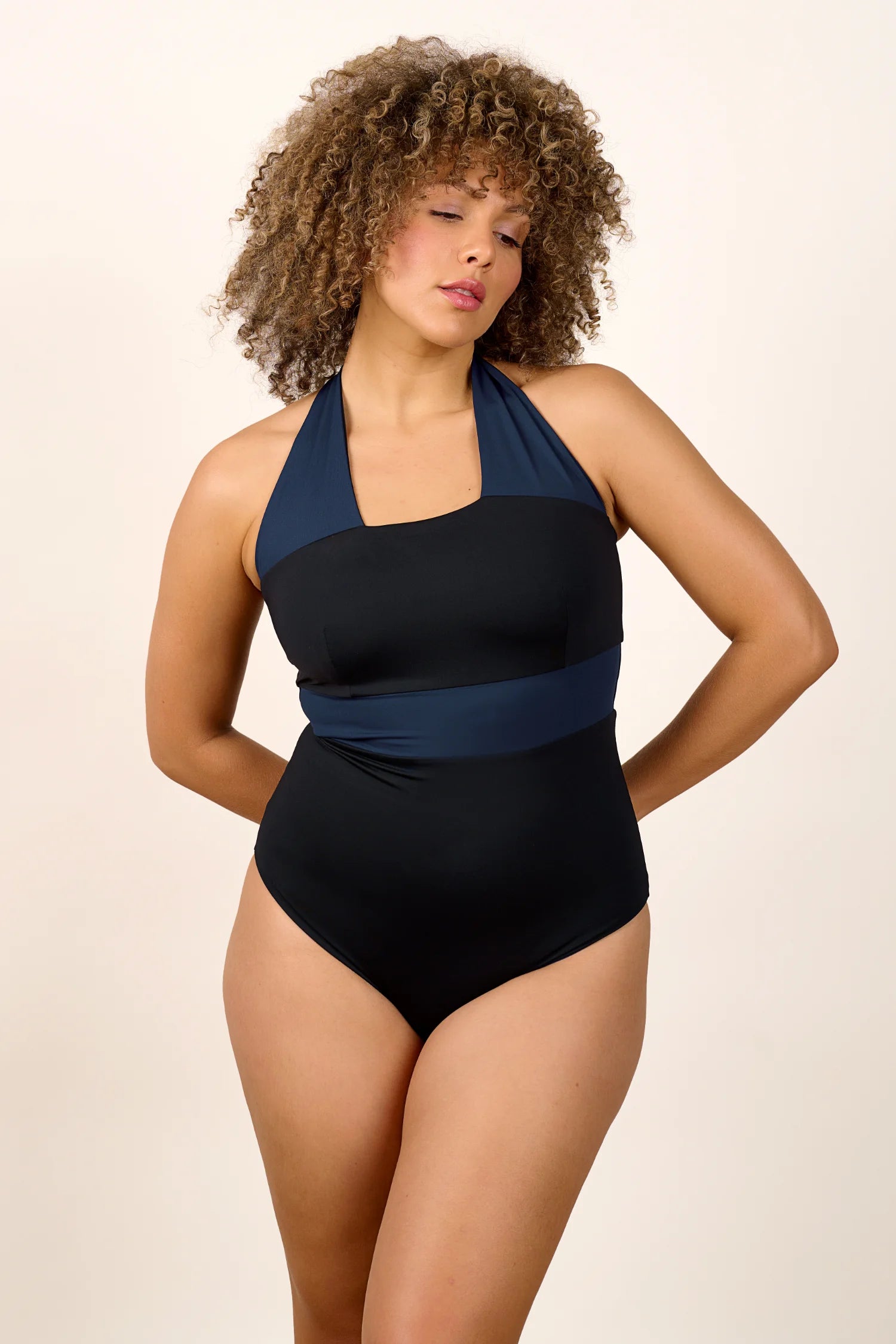 Person trägt einen MYMARINI Neckholder-One-Piece in Schwarz mit dunkelblauen Details.#color_black-navy