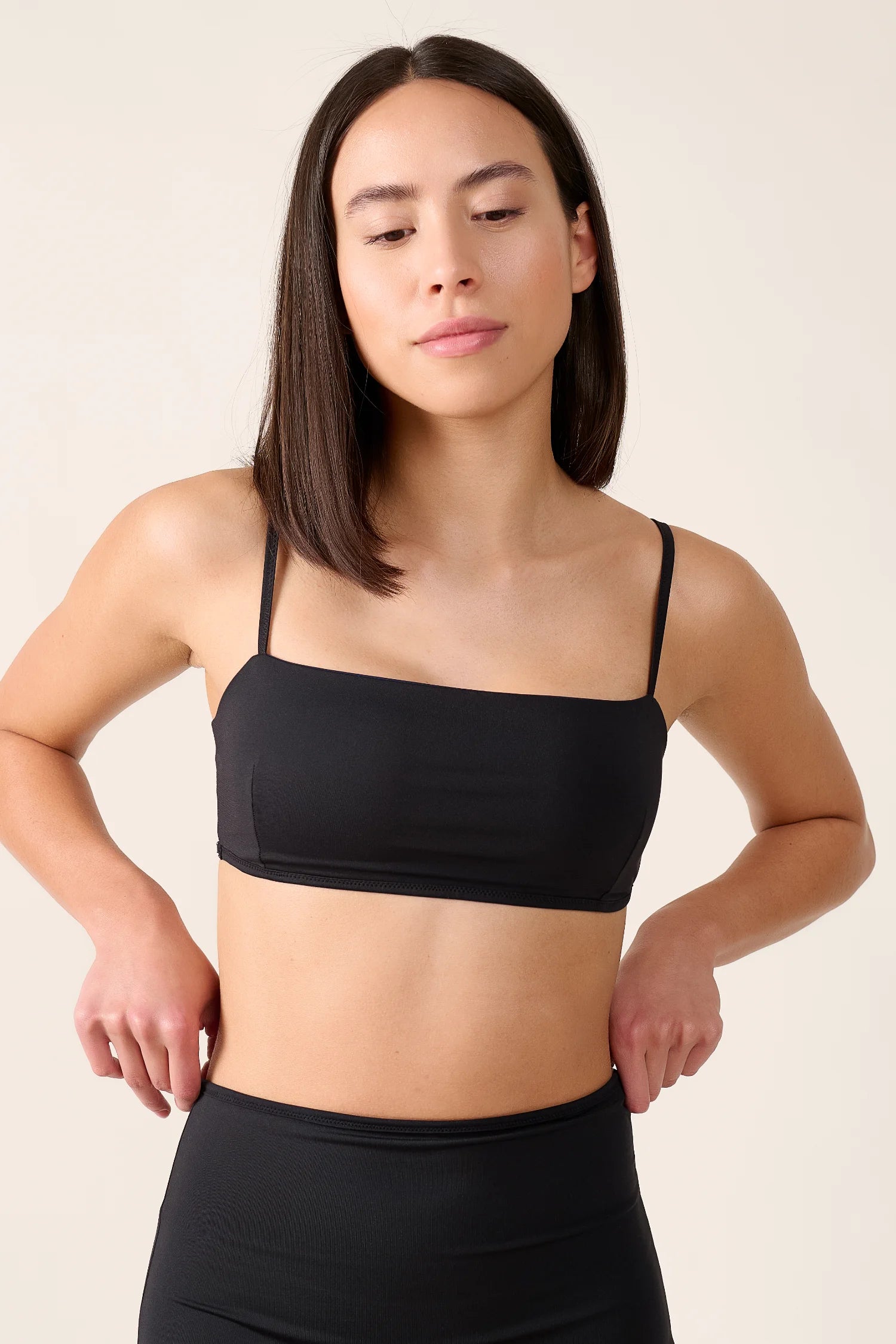 Frau trägt schwarzes MYMARINI Bikinitop mit Spaghettiträgern und hoch geschnittene Bikinihose.#color_black-navy