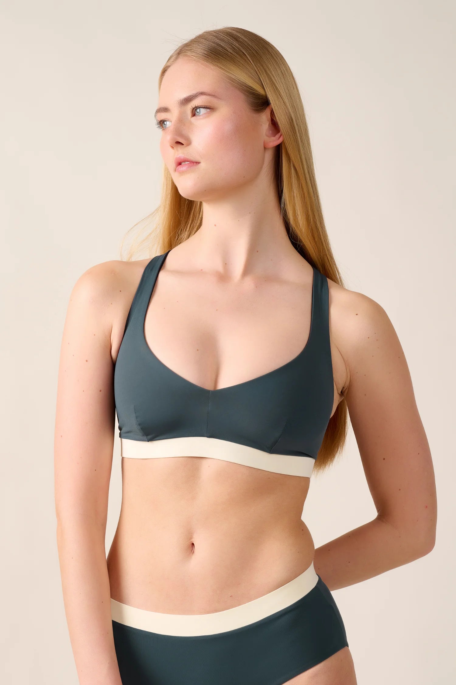 Frau trägt MYMARINI Bikinitop mit breiten Trägern und V-Ausschnitt in Dunkelgrün.#color_black-grey-white