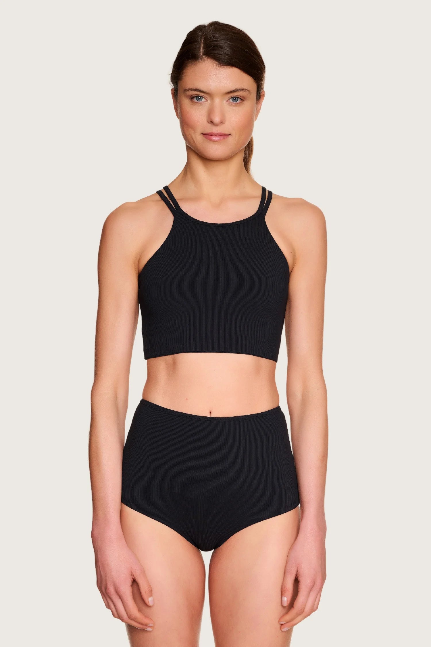 Frau trägt MYMARINI Bikinitop mit breiten Trägern und hoch geschnittene Bikinihose in Schwarz.#color_black