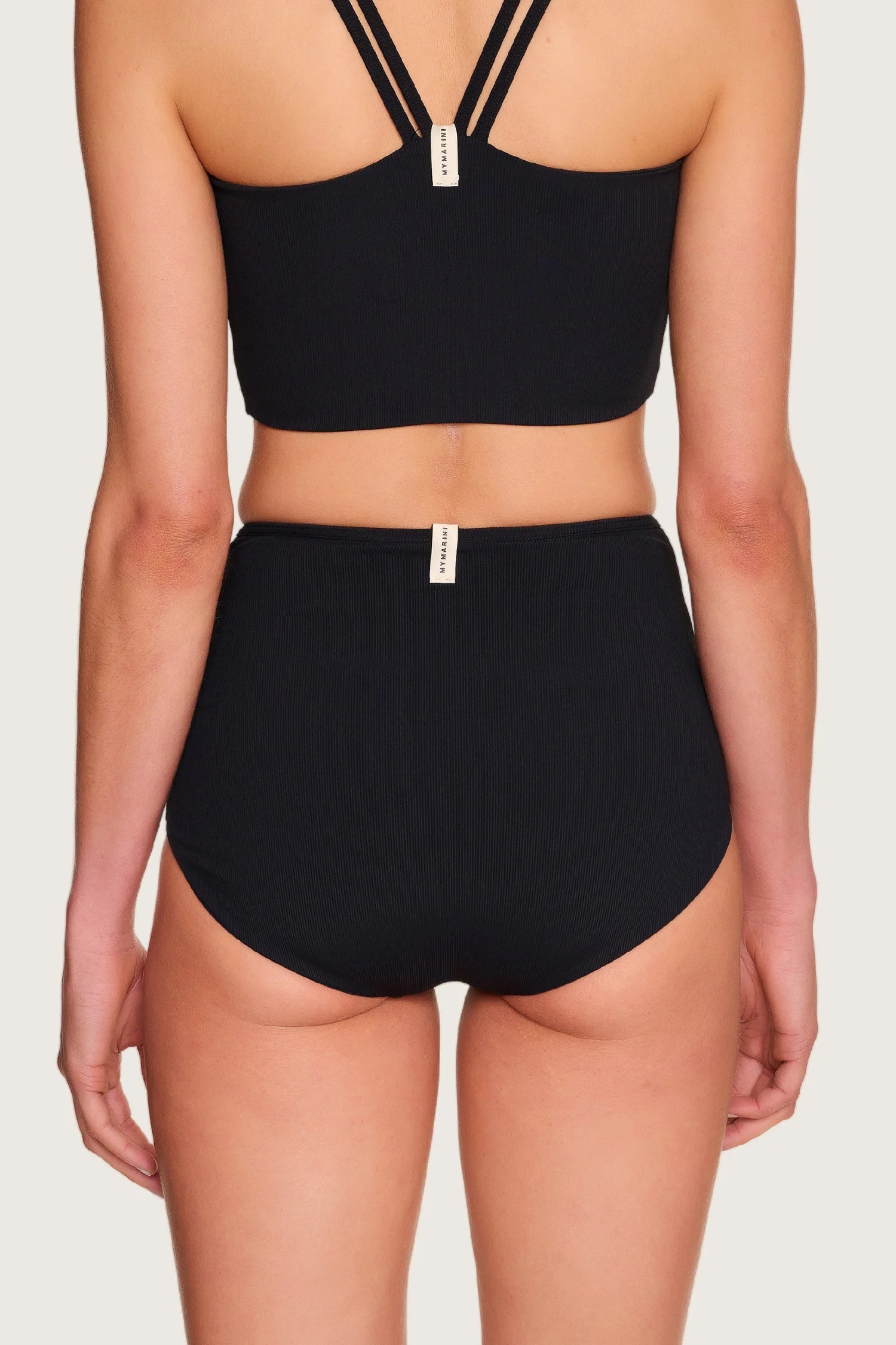 Rückansicht einer Person in schwarzem MYMARINI-Bikini mit breiten Trägern und High-Waist-Schnitt.#color_black